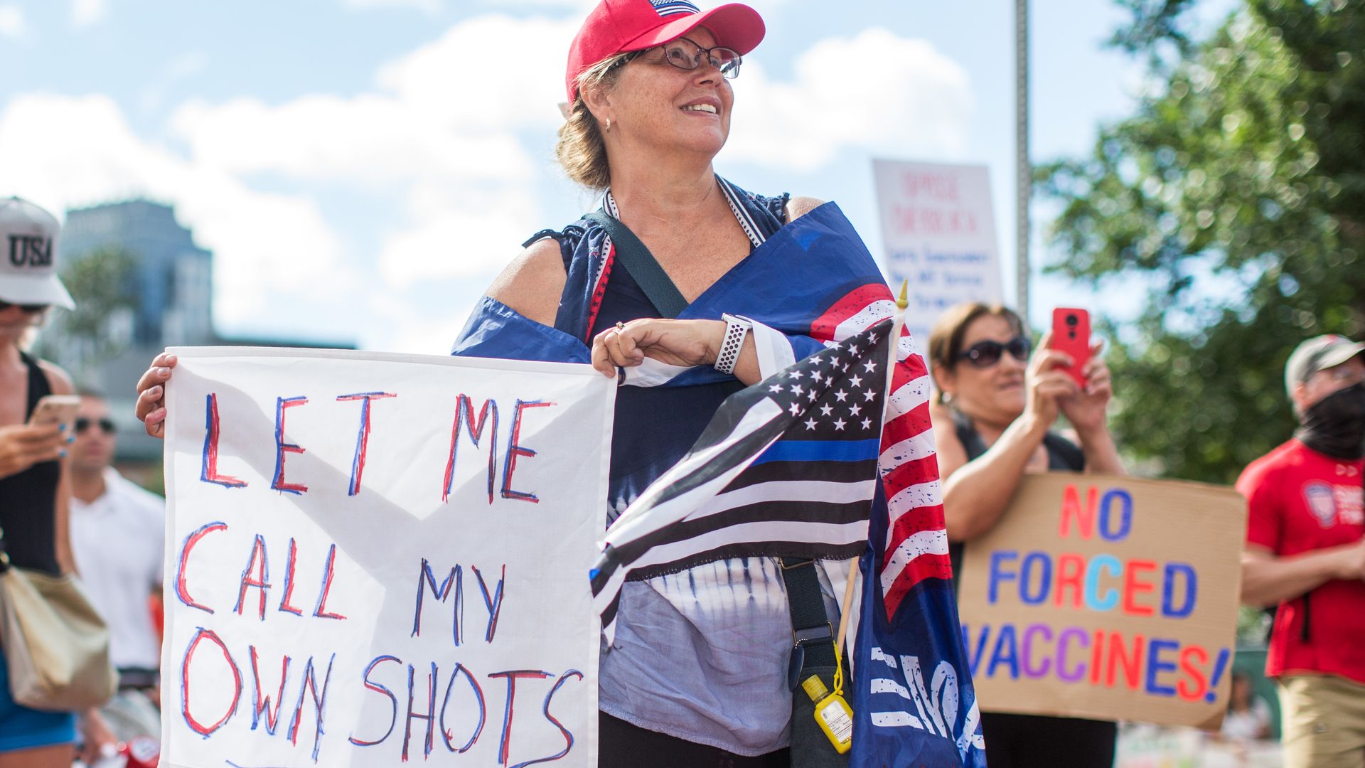 A woman holds a sign that says 'Let me call my own shots.'