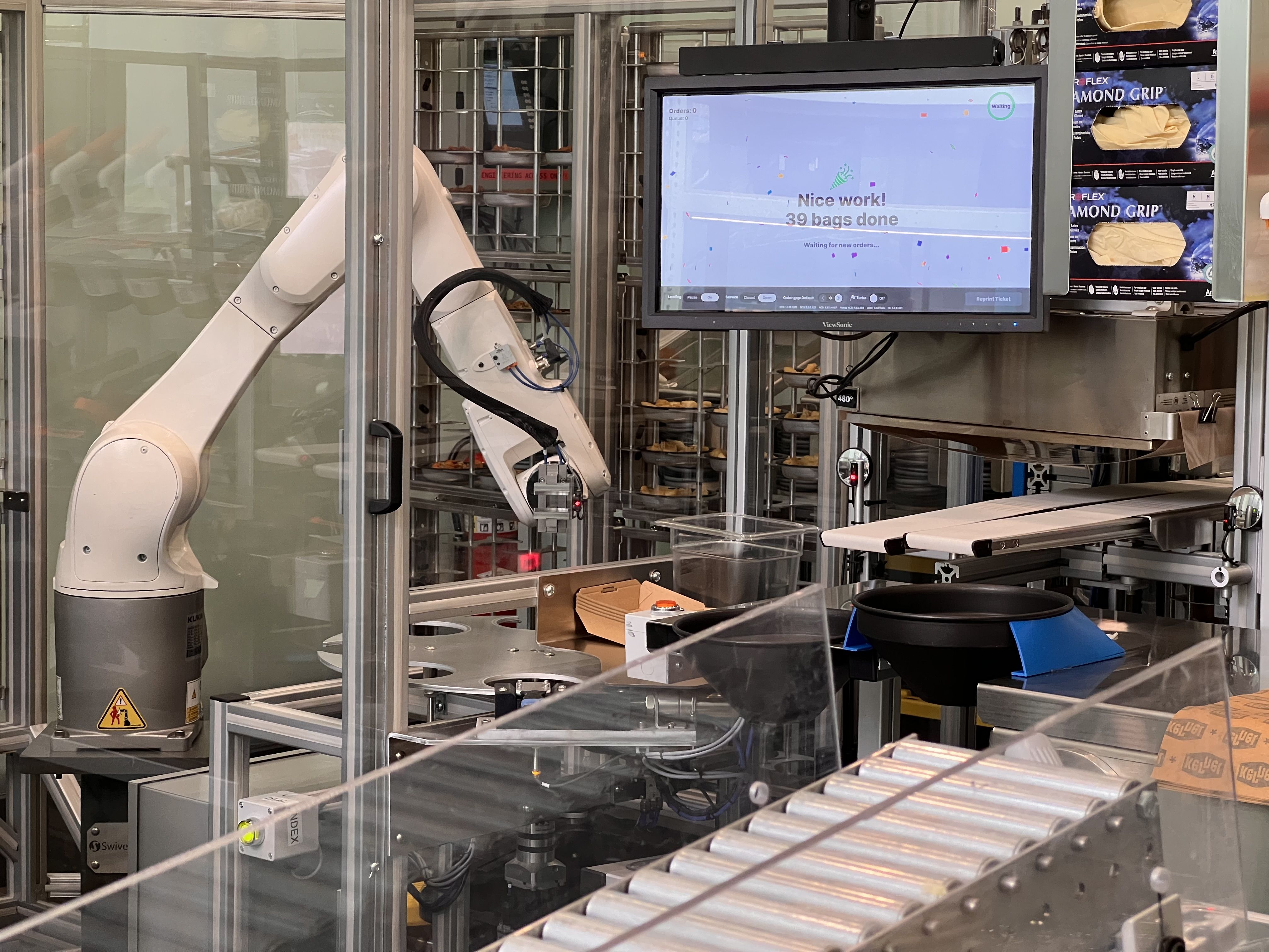 A robot arm prepares food nest to a screen that displays order progress.