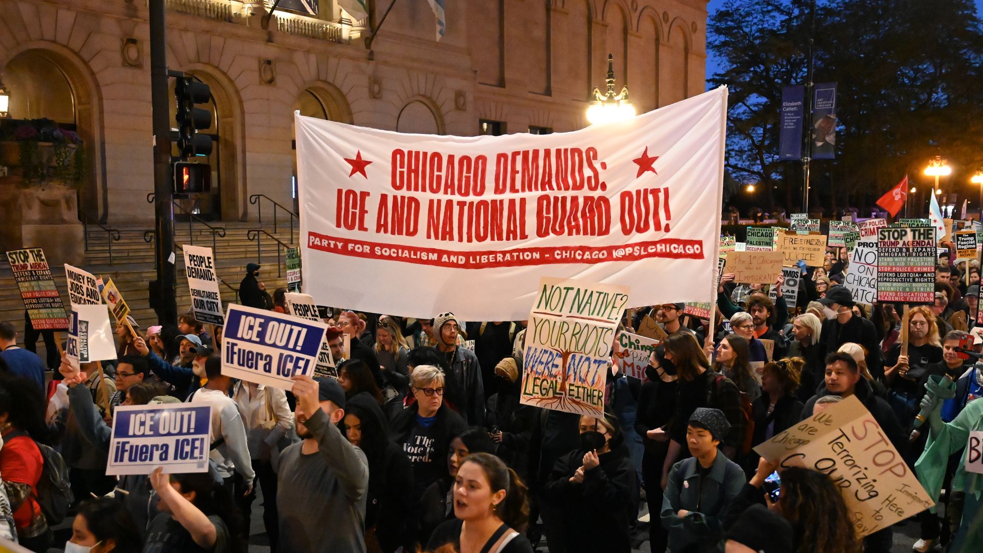 Protesters gather and hold signs demanding the National Guard to leave Chicago. 