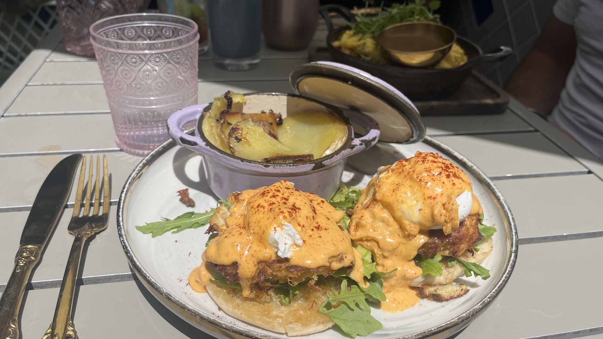 A crab cake benedict with a side of potatoes on a plate.