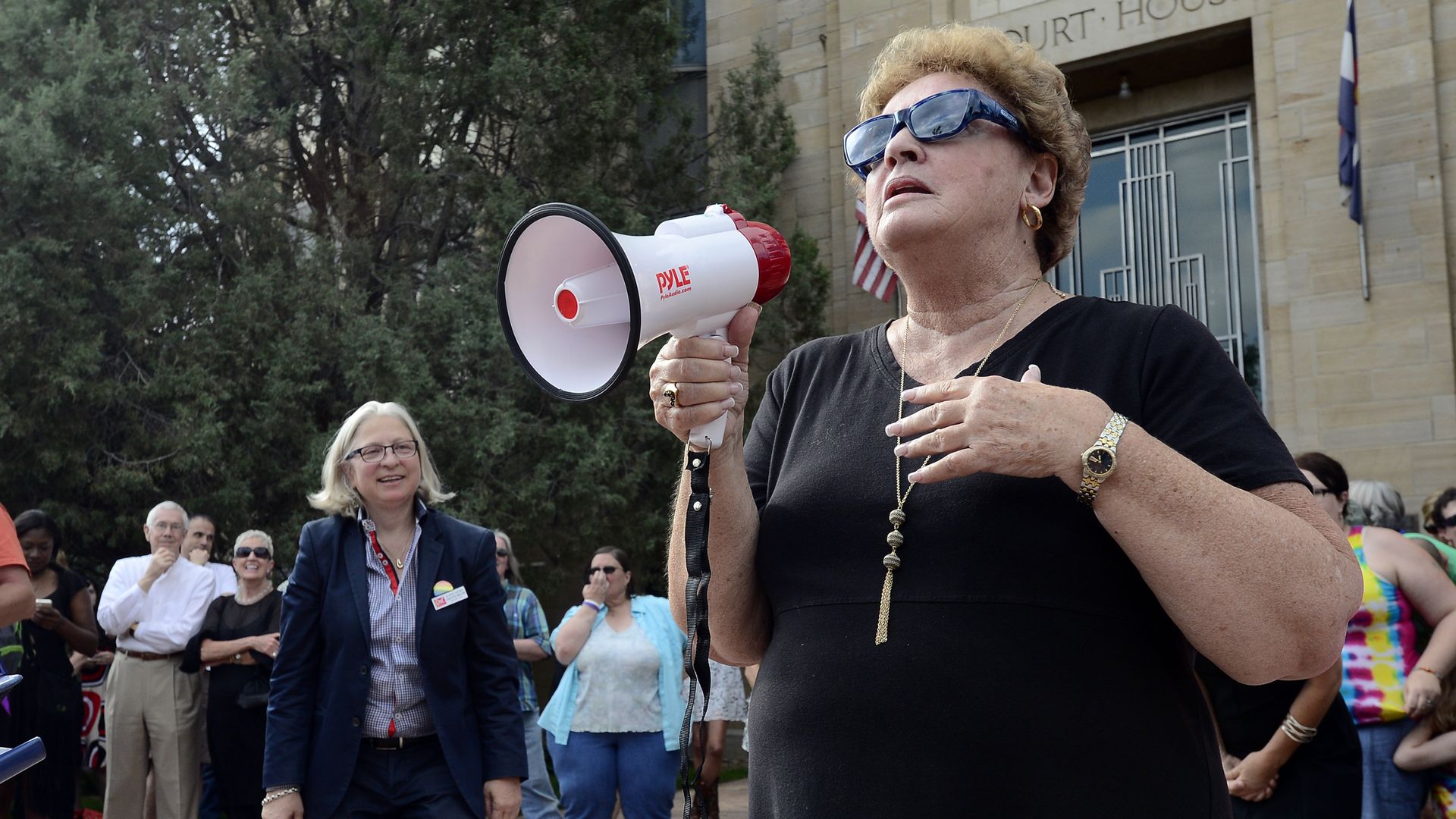 Former Boulder County Clerk Clela Rorex speaks through a megaphone to a crowd in front of the Boulder County Courthouse.