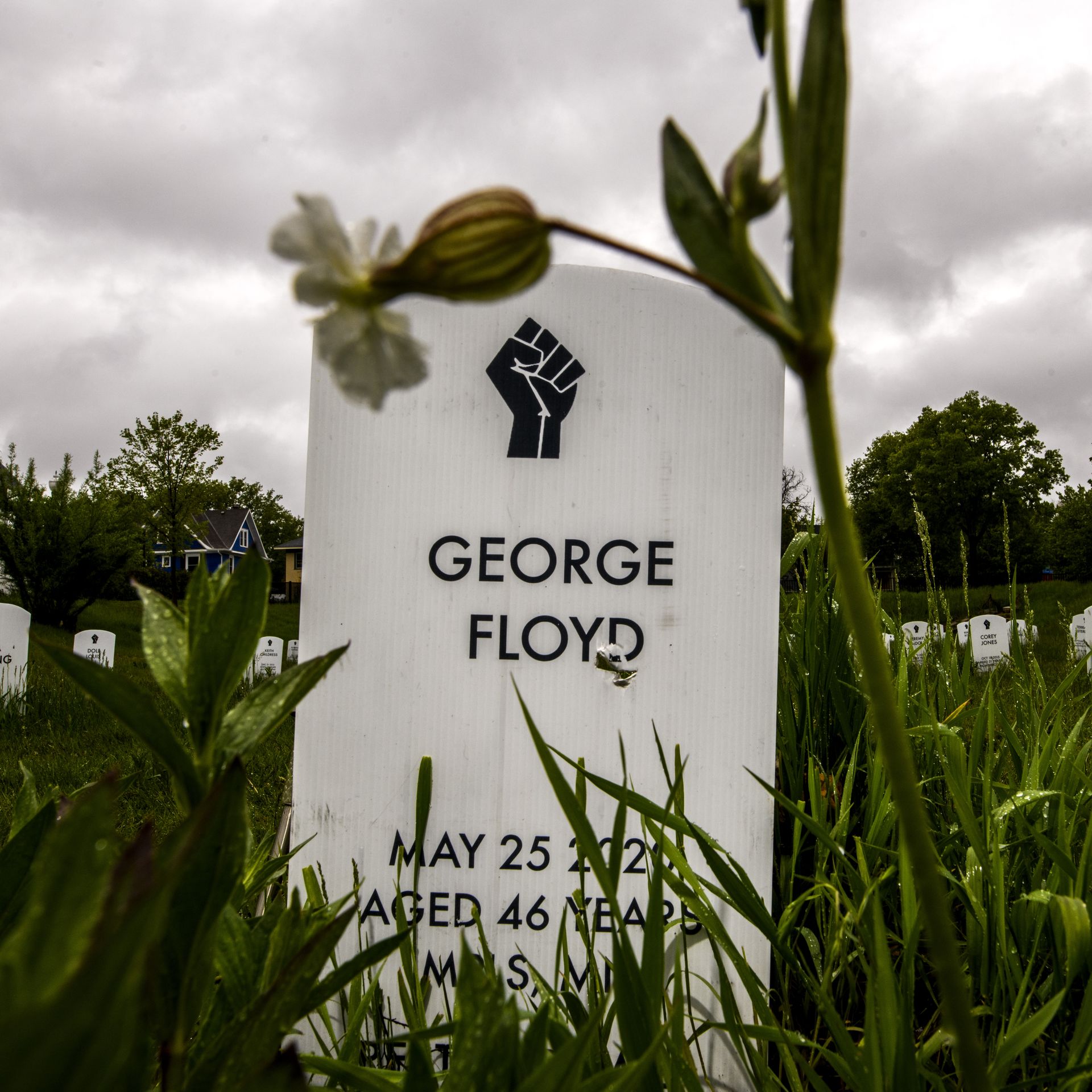 Photo of a white gravestone with George Floyd's name and the image of a fist engraved on it