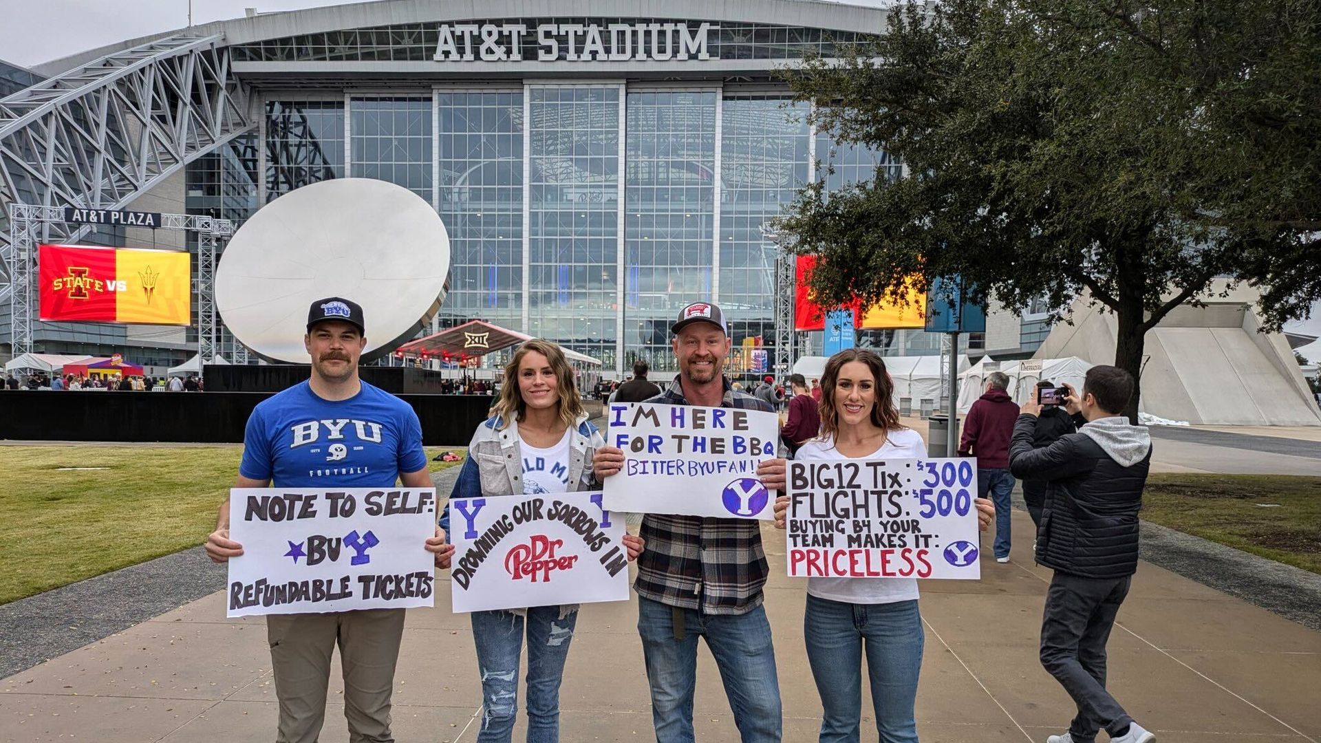 A group of people stand holding signs in front of a stadium
