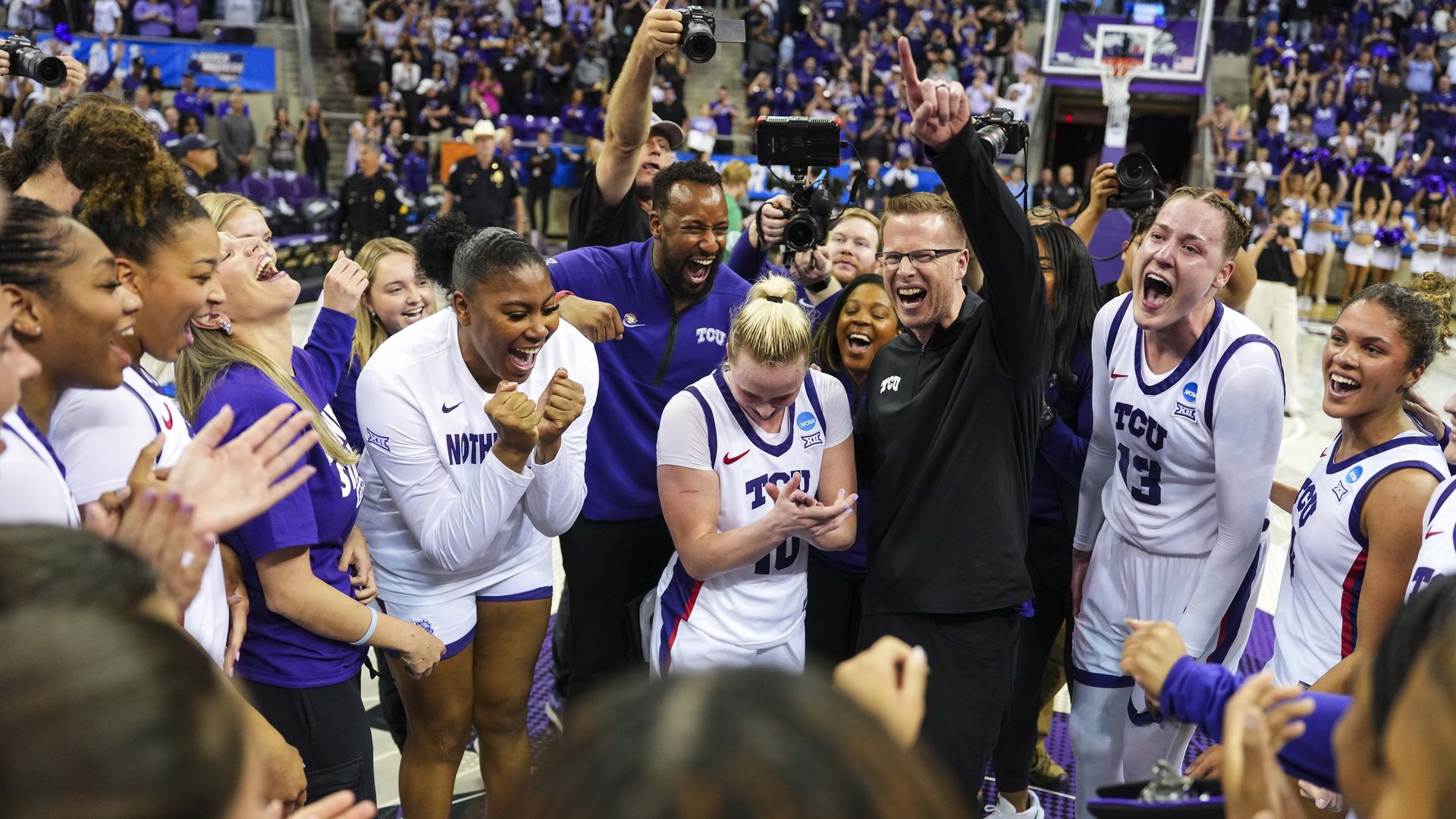 Women's basketball players circle around each other, looking happy