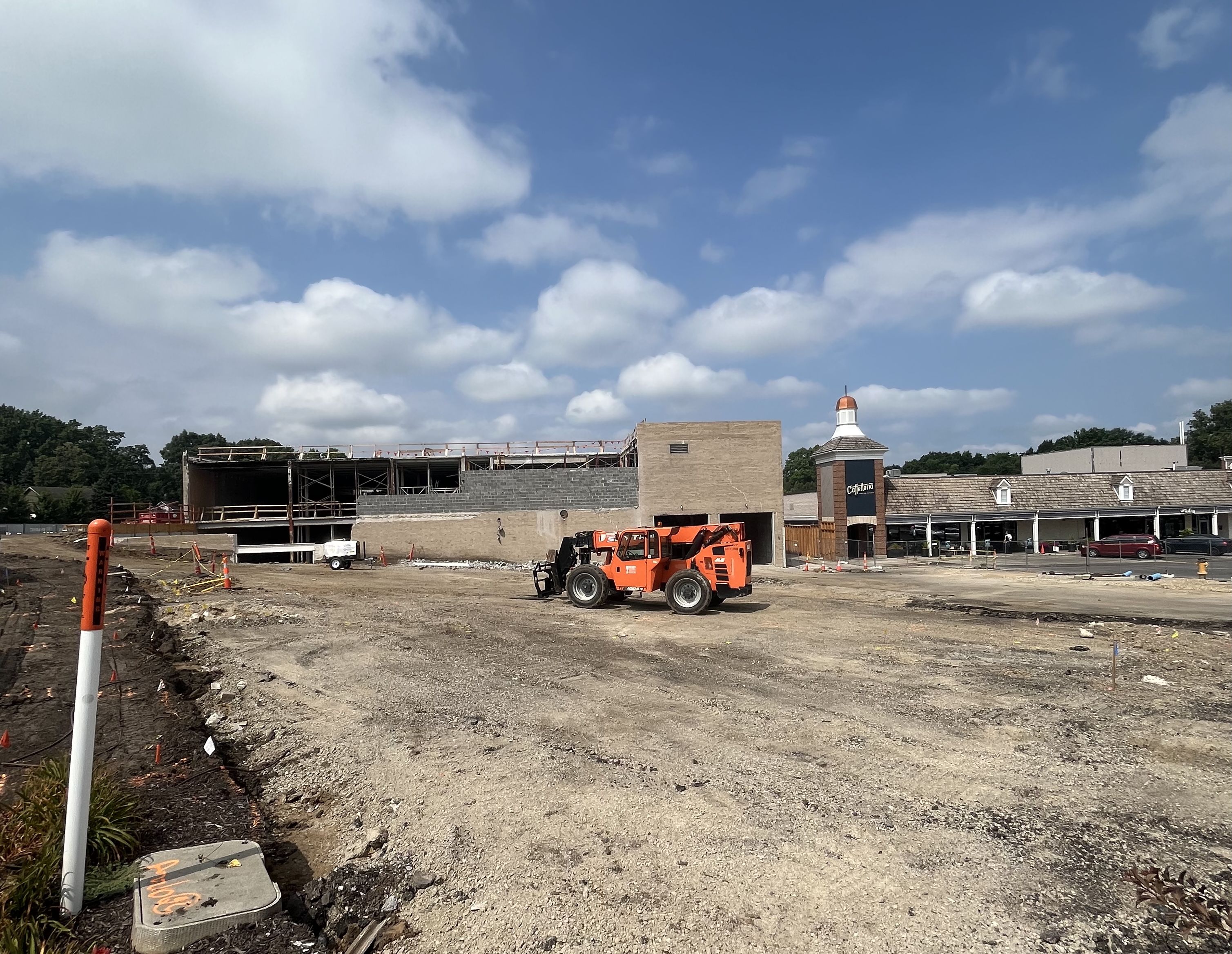 Orange construction vehicle on dirt lot in front of the old Macy's building at The Shops of Prairie Village.