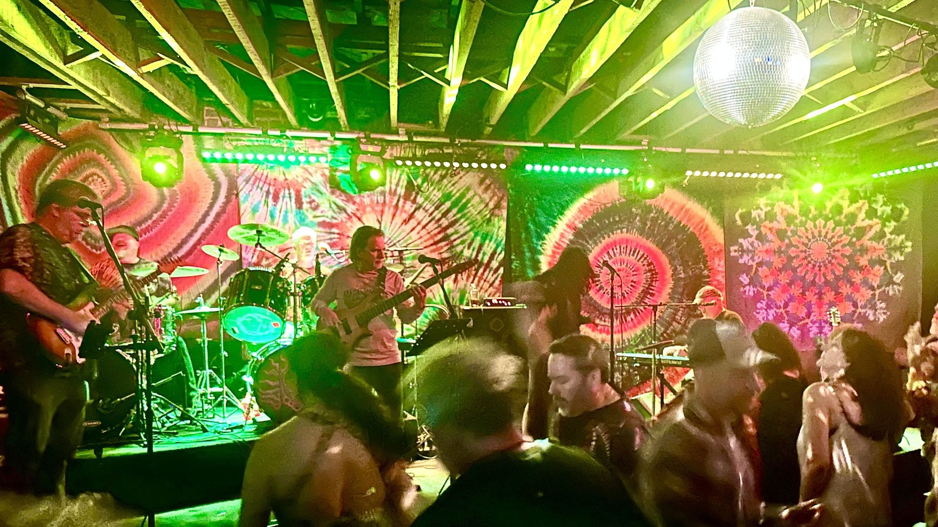 Fans dance to a band playing in front of a wall of tie dye tapestries 