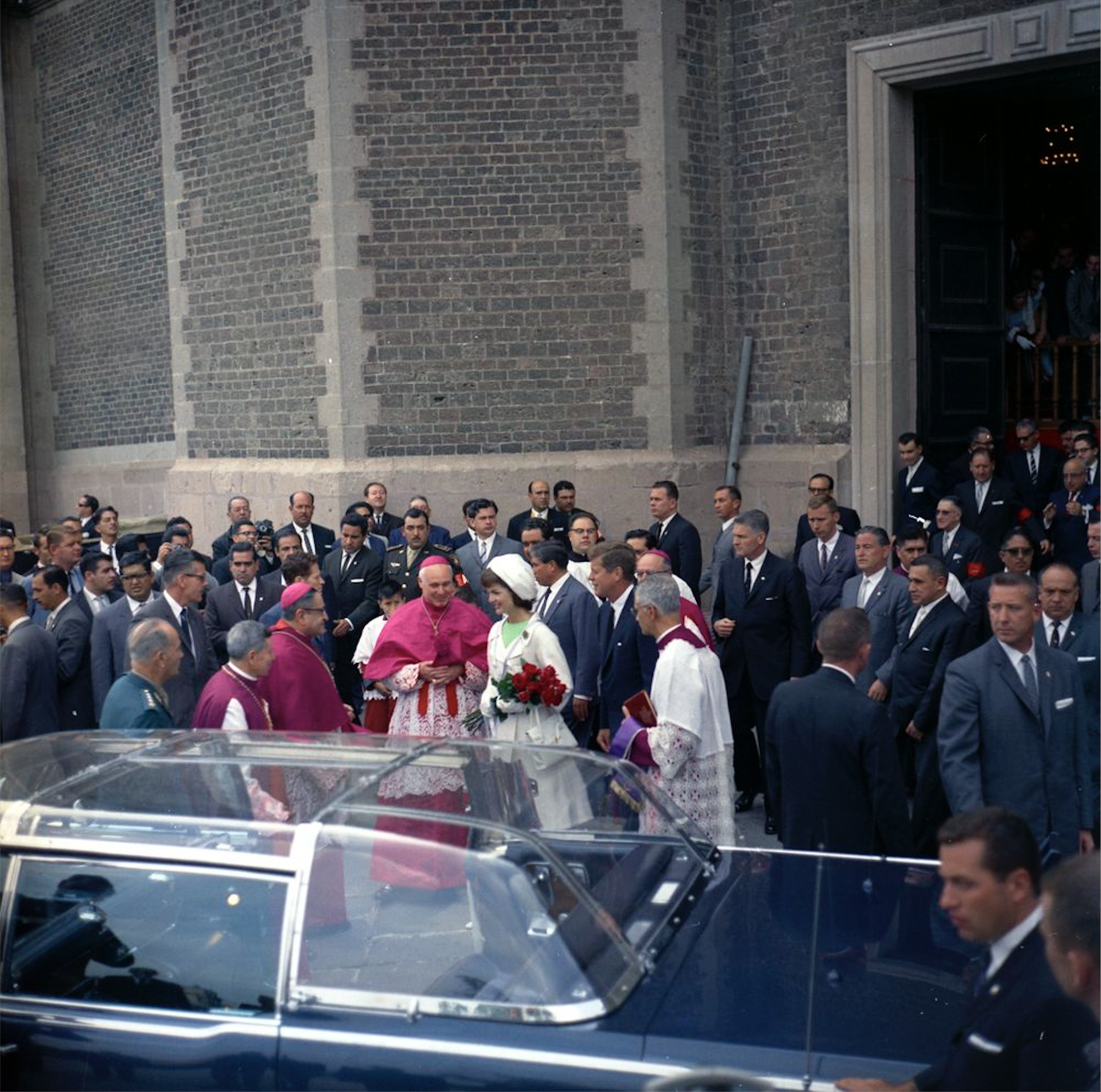 President John F. Kennedy and First Lady Jacqueline Kennedy walk toward the Presidential limousine (Lincoln-Mercury Continental with bubble-top) following mass at the Basílica de Nuestra Señora de Guadalupe (Basilica of Our Lady of Guadalupe) in Mexico City, Mexico. 