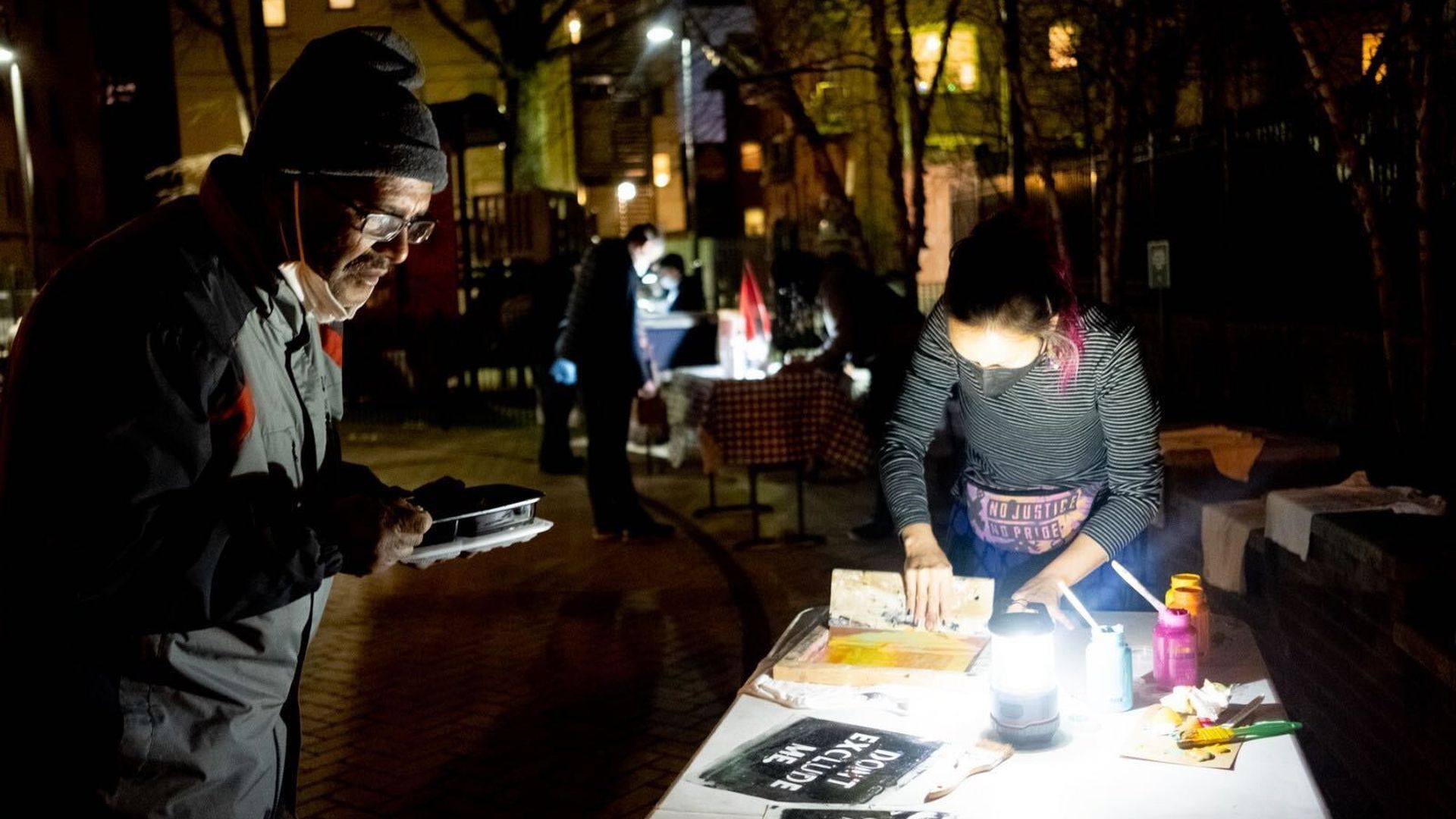 A man looks at a table where signs are being painted.