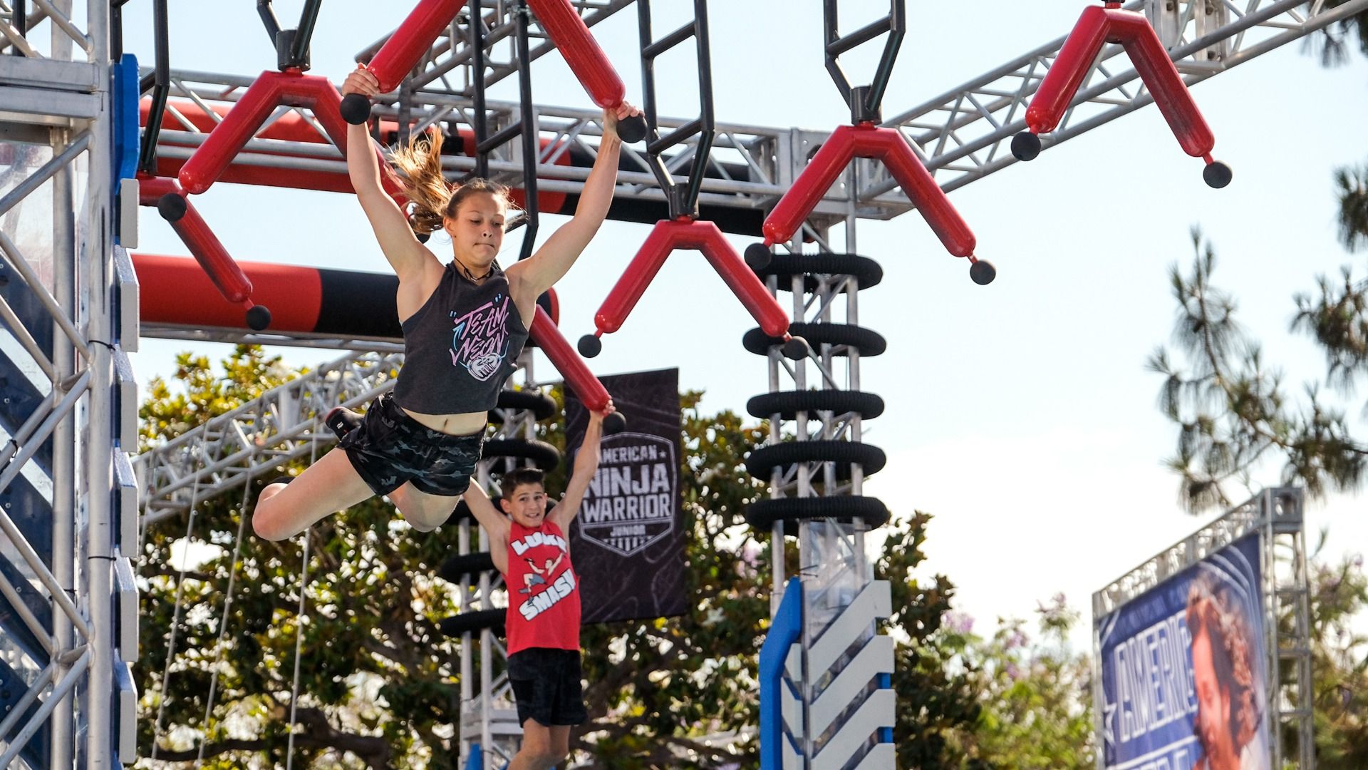 Contestant Jordan Carr swings on a red obstacle course in "A New Generation Takes the Course" Episode 301 of "American Ninja Warrior Junior."
