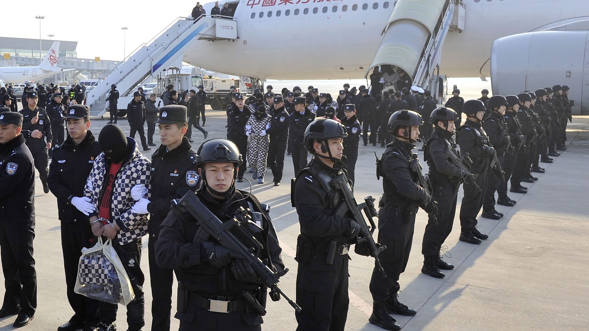 104 telecom fraud suspects returned to China under police escort at airport strip.