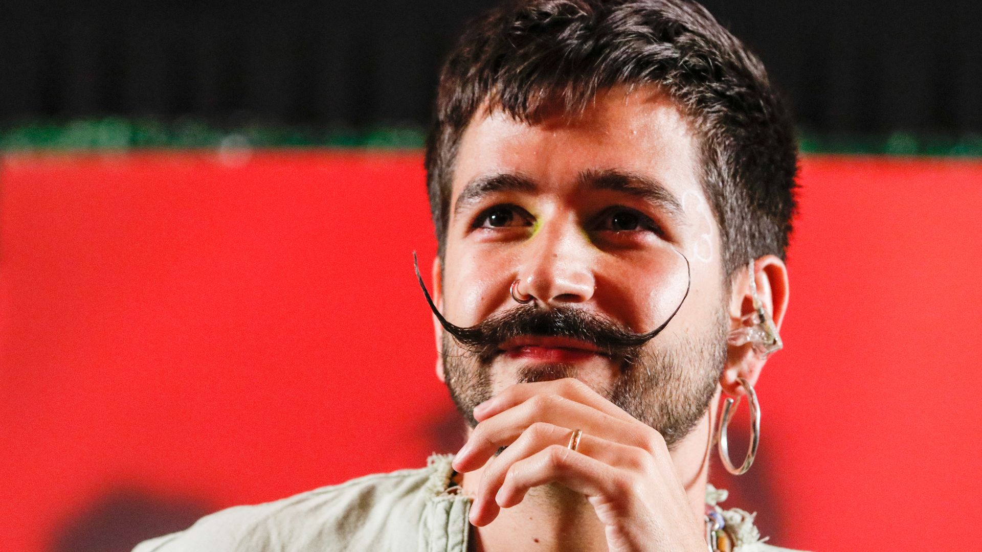 Caolombian singer Camilo has a handlebar mustache and smiles.
