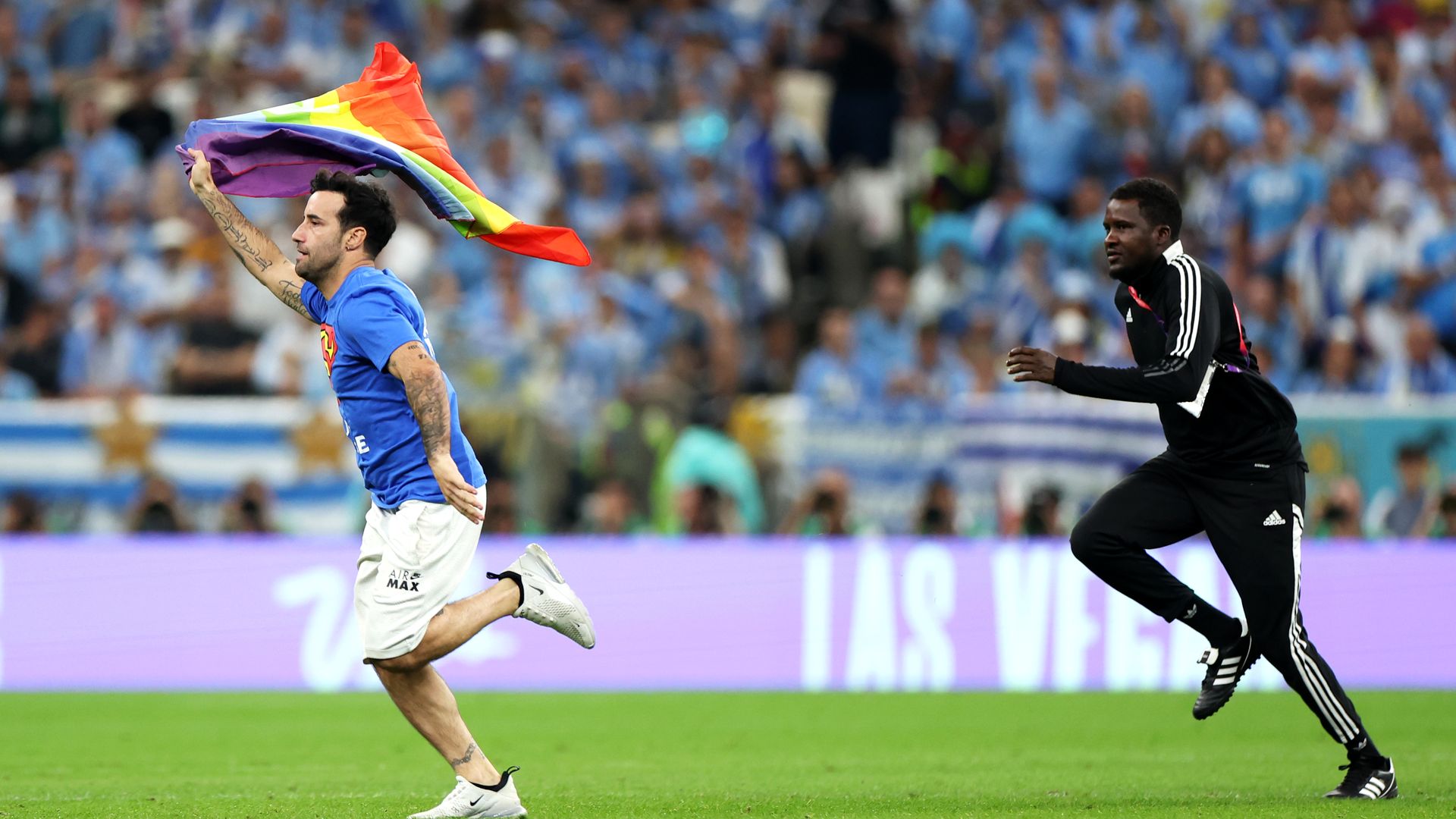Photo of a protester holding a rainbow flag runs across the pitch at a World Cup soccer match