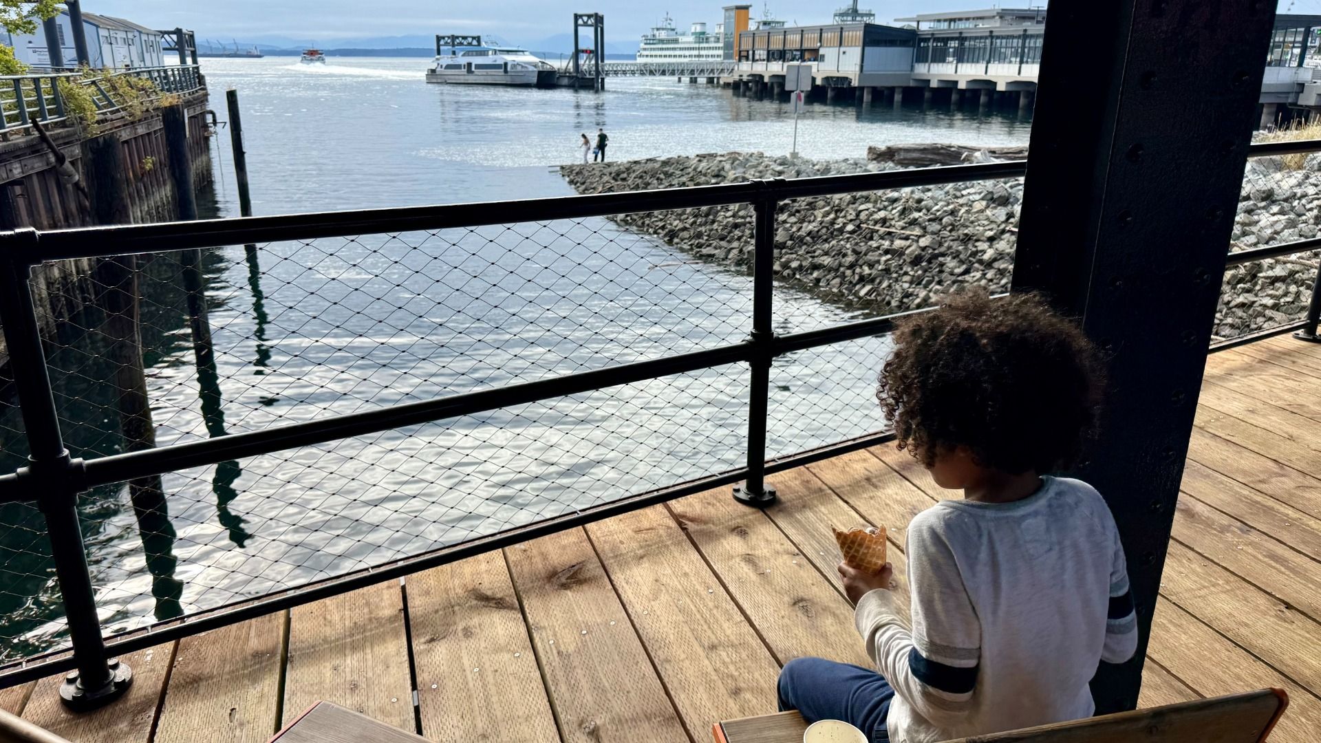 A child sits overlooking the water on a pier in Seattle. 