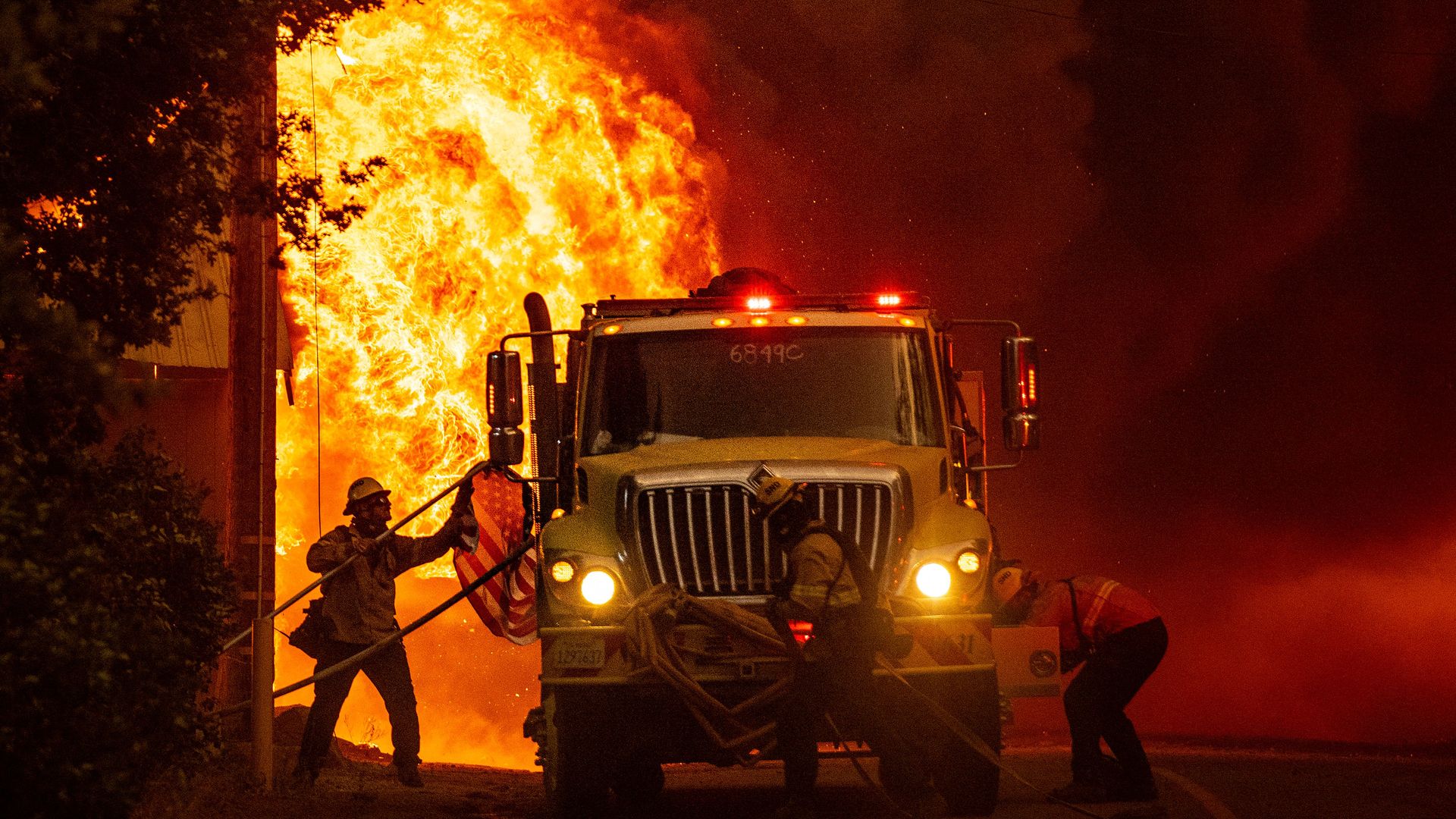 A firefighter from San Diego, saves an American flag as flames consume a home during the Dixie fire in Greenville, California on August 4, 2021.