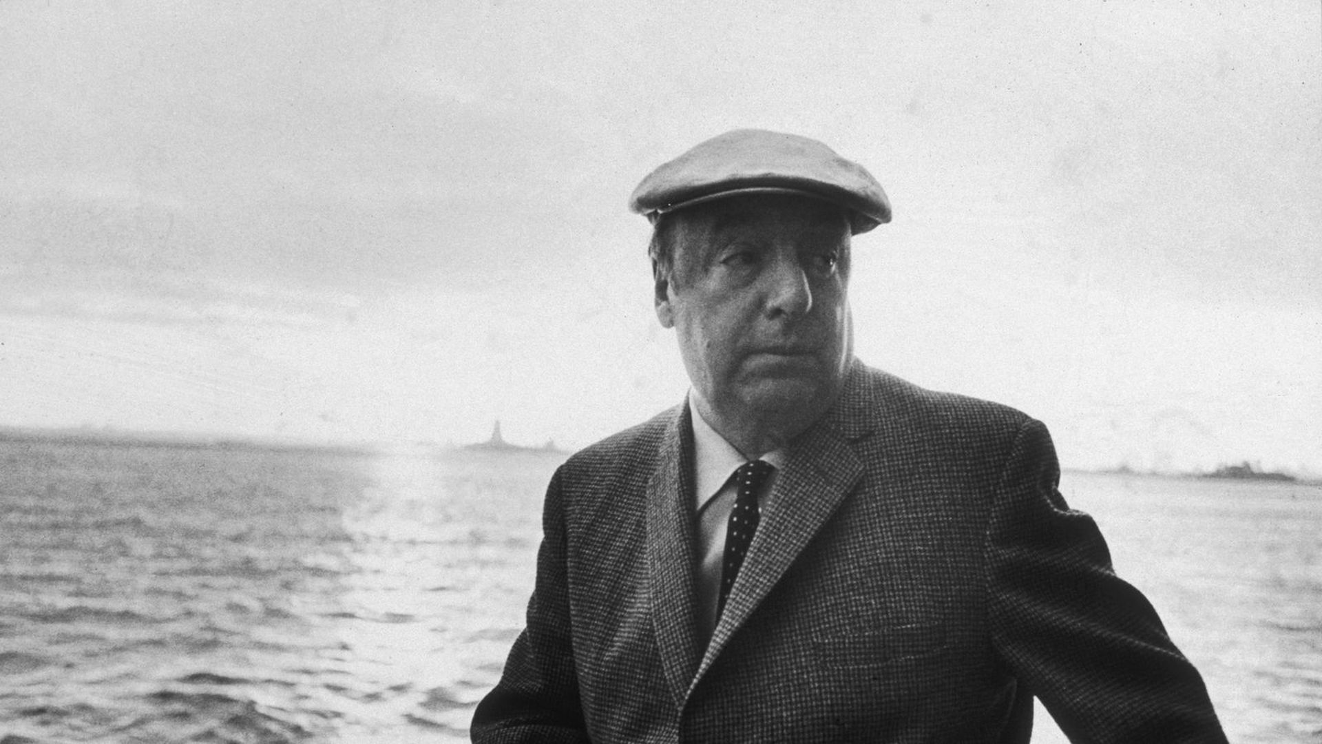 a black and white photo of Pablo Neruda on a ship in the ocean looking off to his right