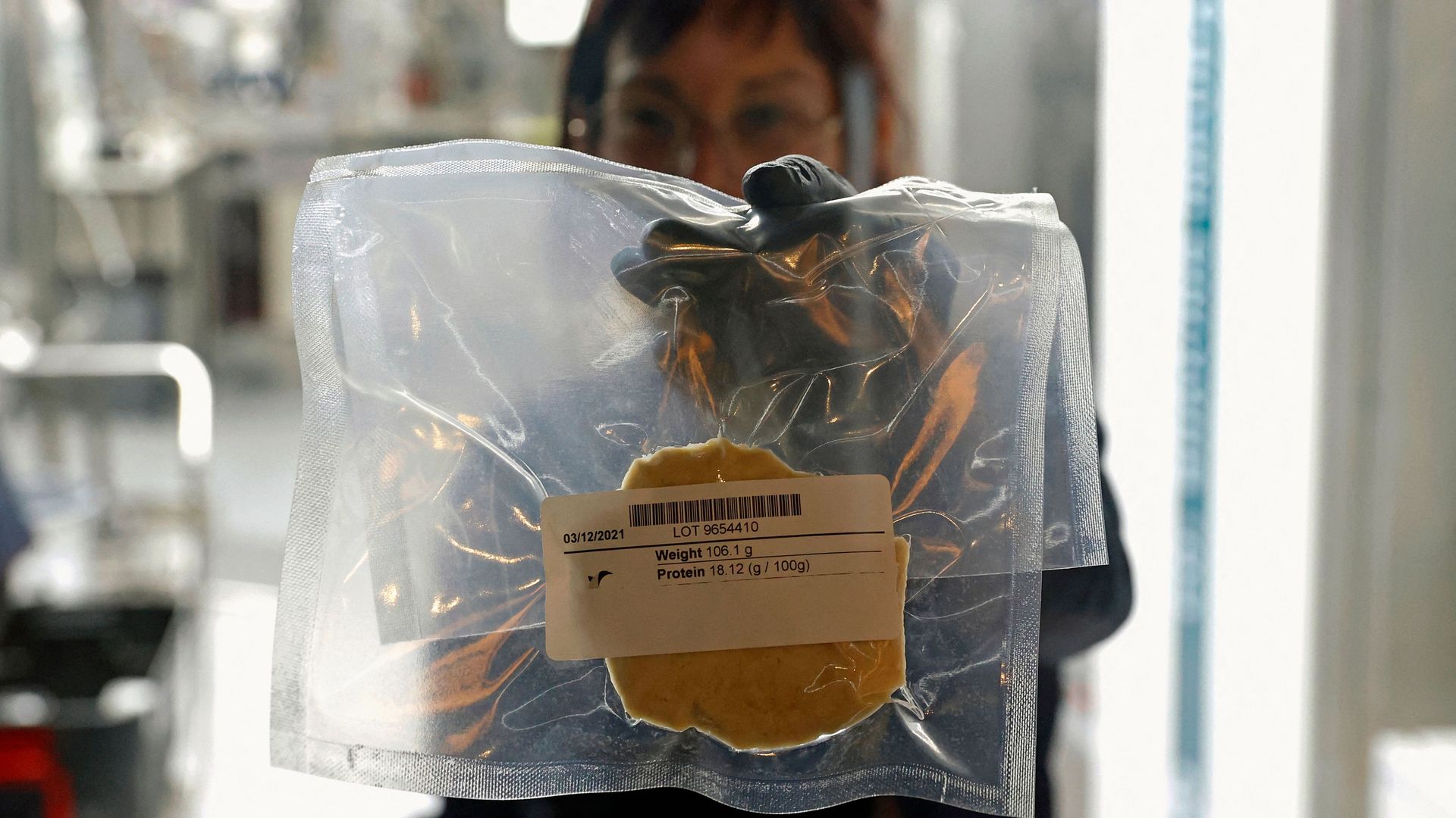 A technician displays a lab-grown chicken meat in a sealed bag.