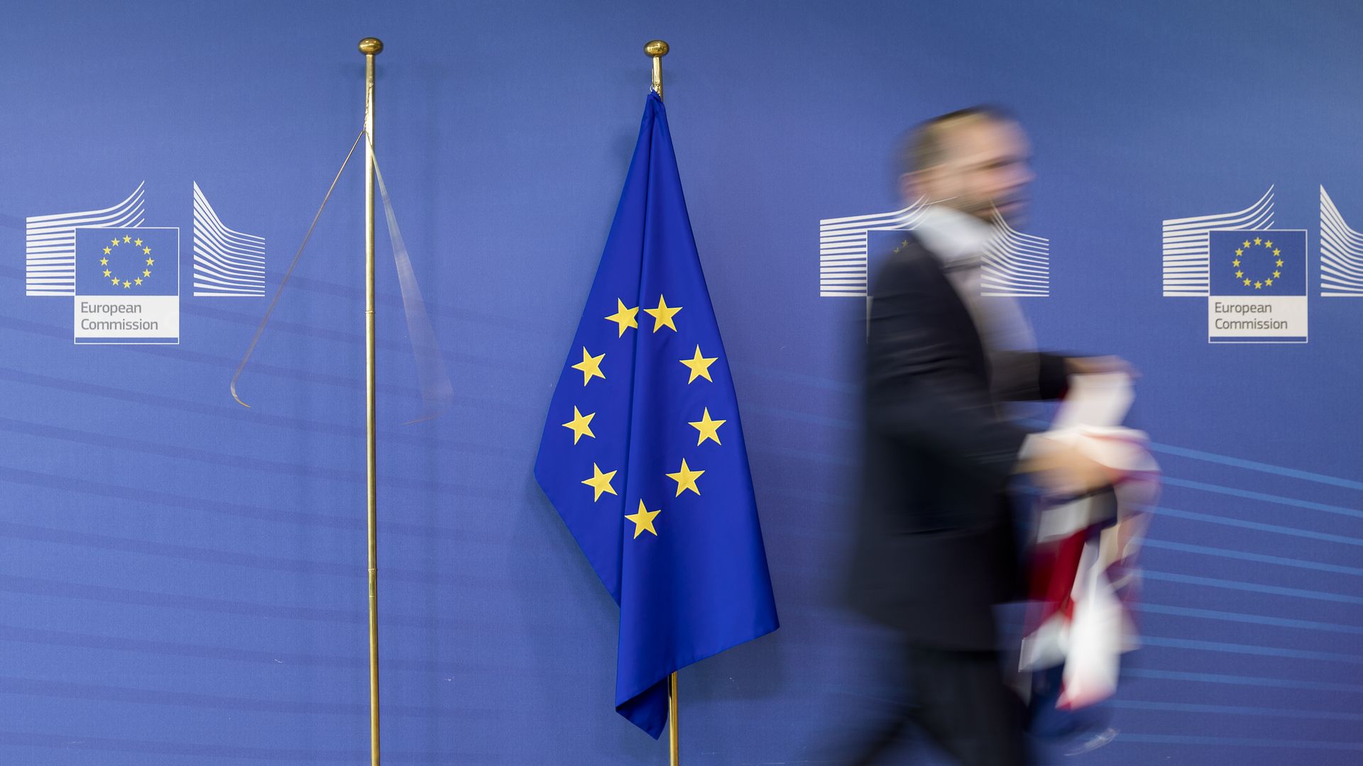 The flag of the European Union with a man walking away from it holding the Union Jack
