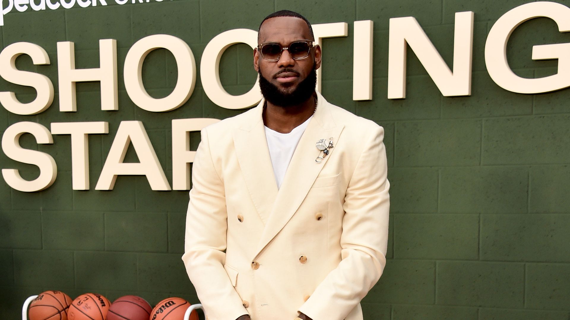 LeBron Jame poses in front of a sign that reads, "Shooting Star." 