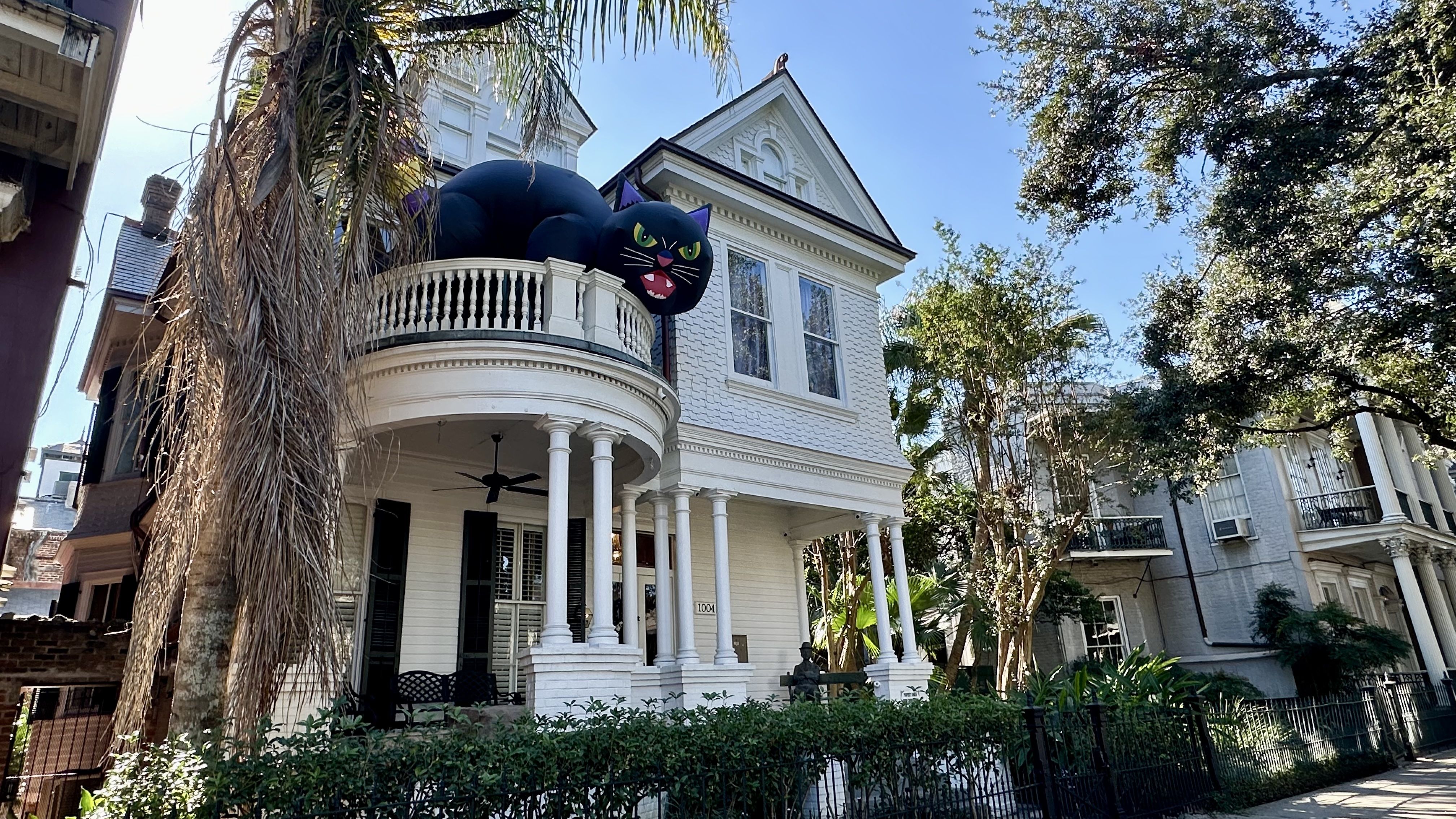 Image shows a white house with an inflatable black cat on the balcony.