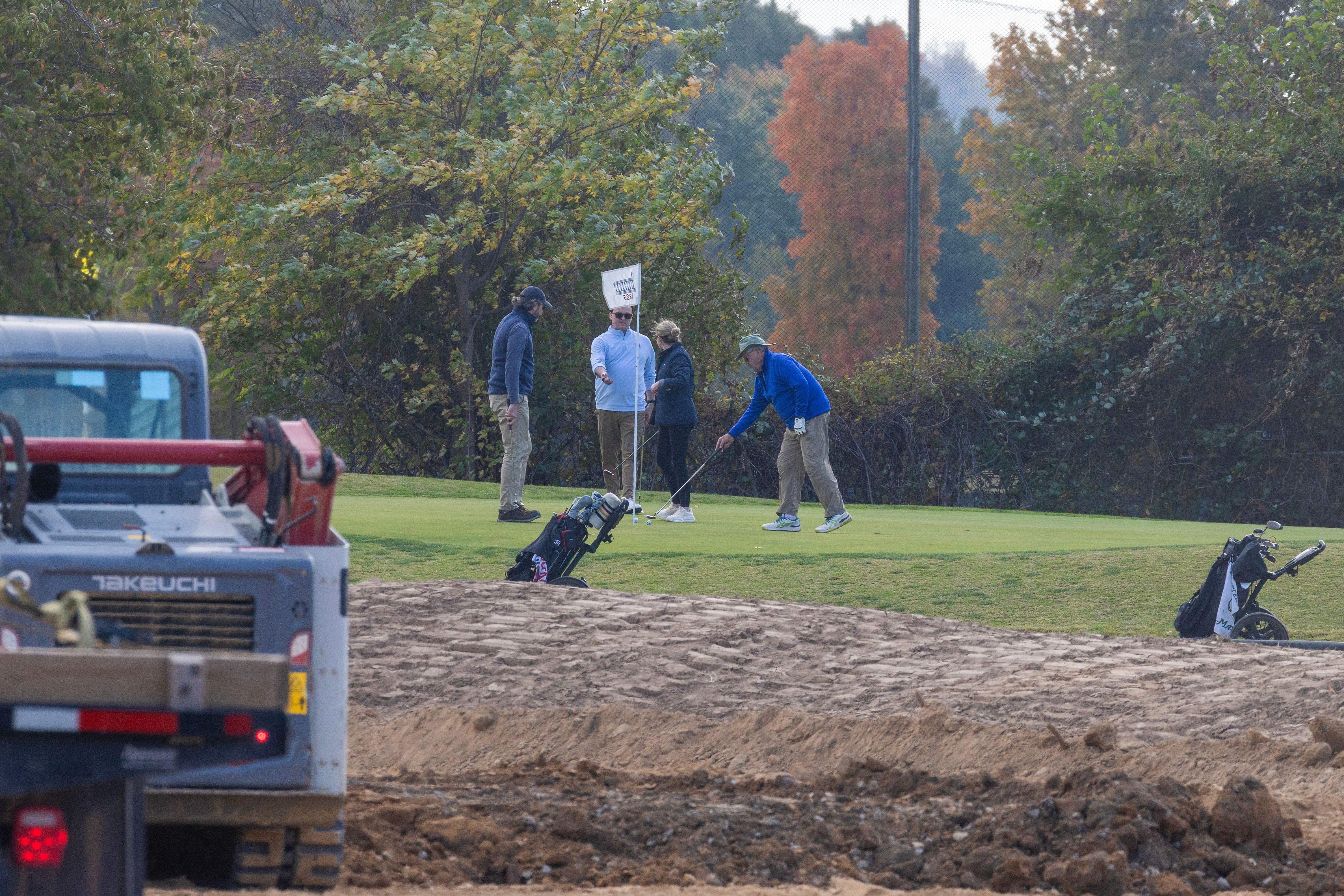 Golfers play as trucks unload debris and soil from the demolition of the White House's East Wing last year. Photo: Tasos Katopodis/Getty Images