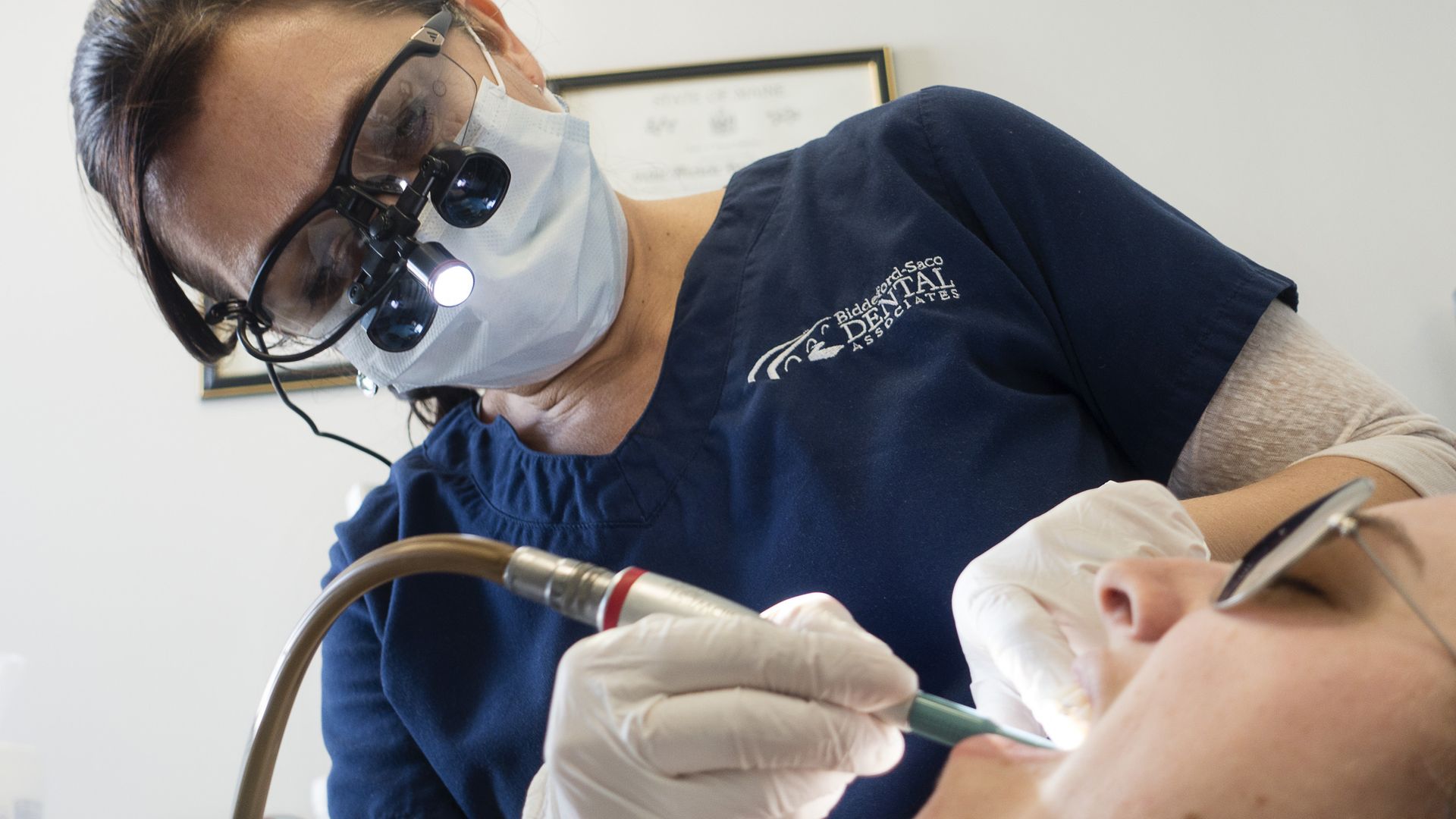 A dental hygienist works in a patient's mouth.