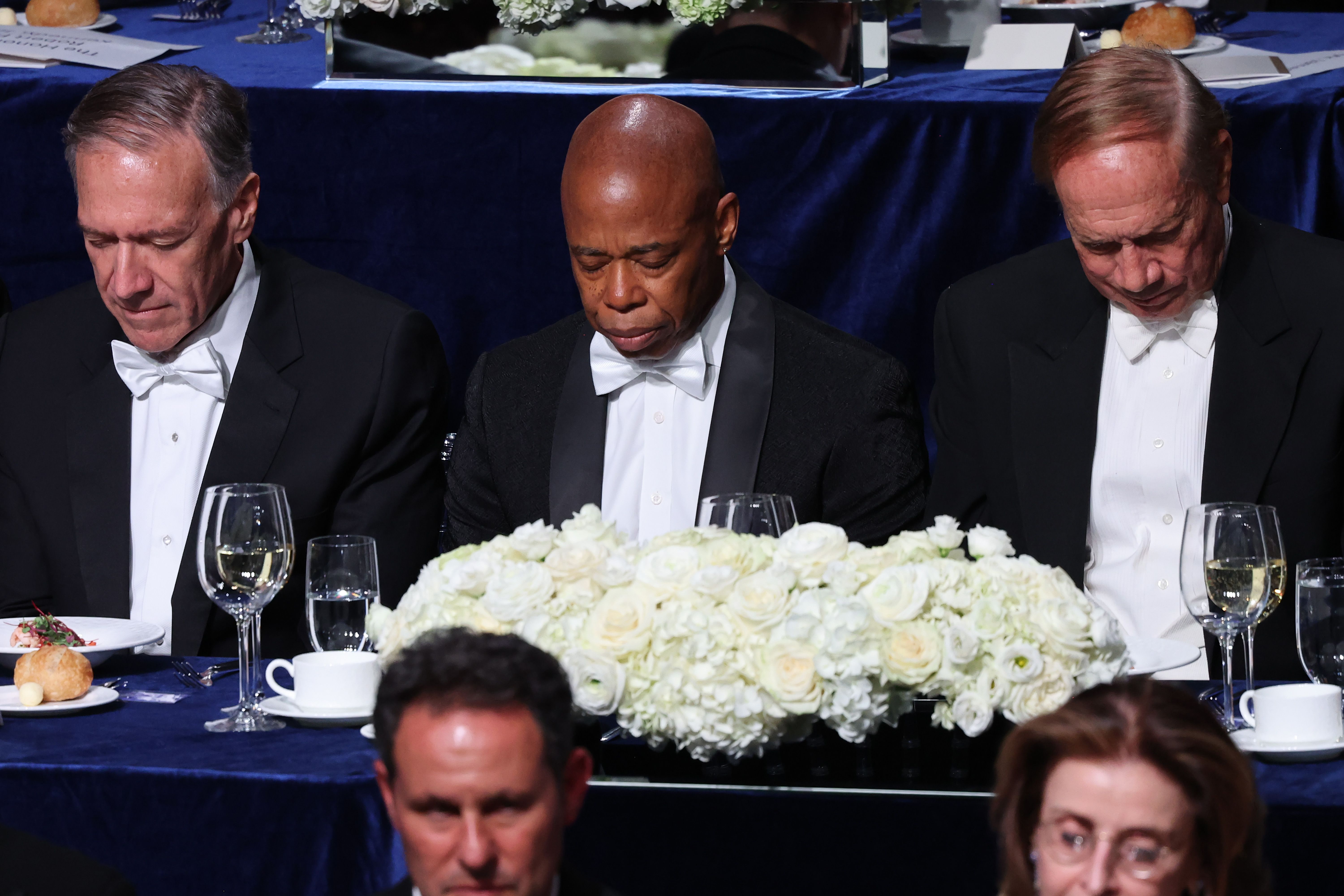  (L-R) Mike Pompeo, former U.S. secretary of state; New York City Mayor Eric Adams; and former New York state Gov. George Pataki, lower their heads in prayer during the annual Alfred E. Smith Foundation Dinner at the New York Hilton Midtown on October 17, 2024 in New York City. 