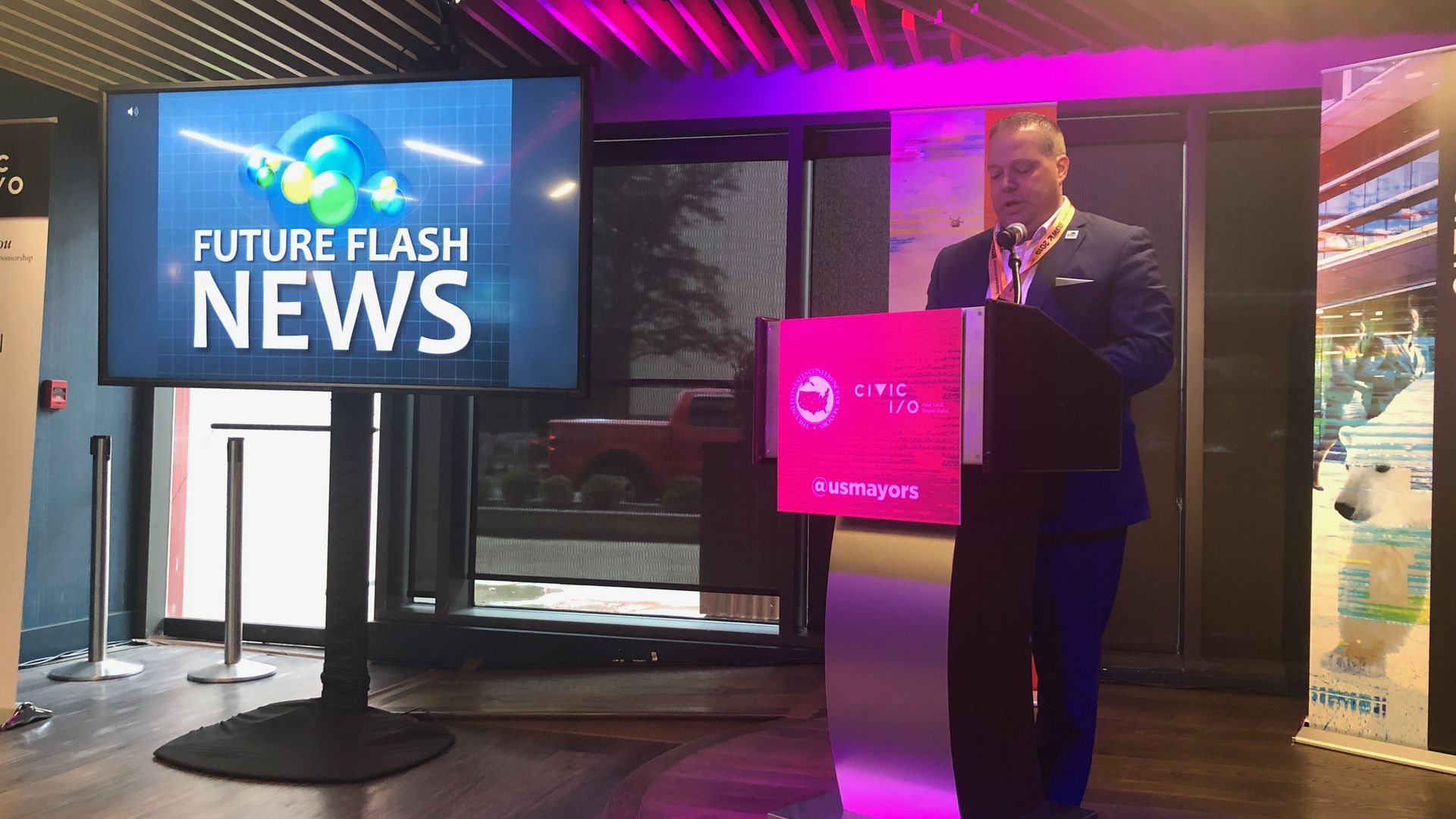 A man stands behind a podium as if reading a news report