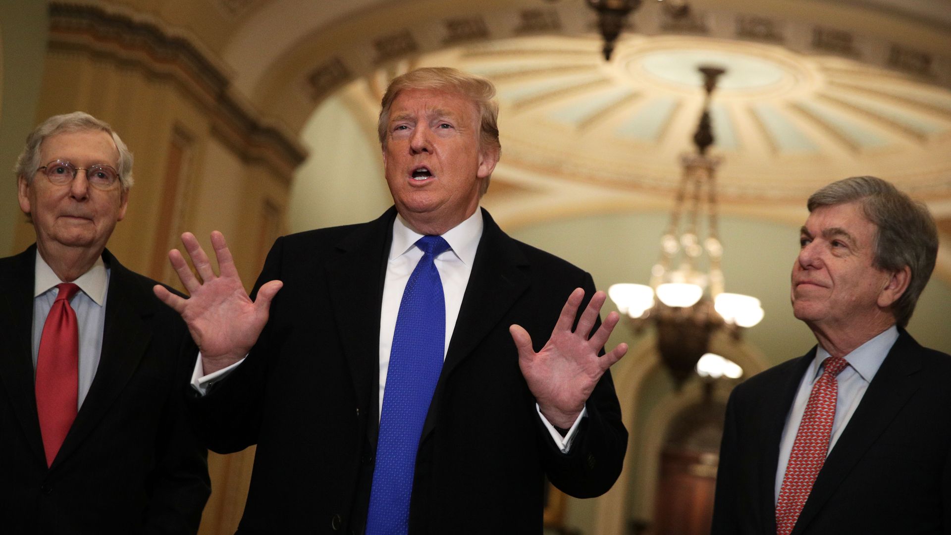 In this image, Trump stands and talks in between Mitch McConnell and Sen. Roy Blunt. 