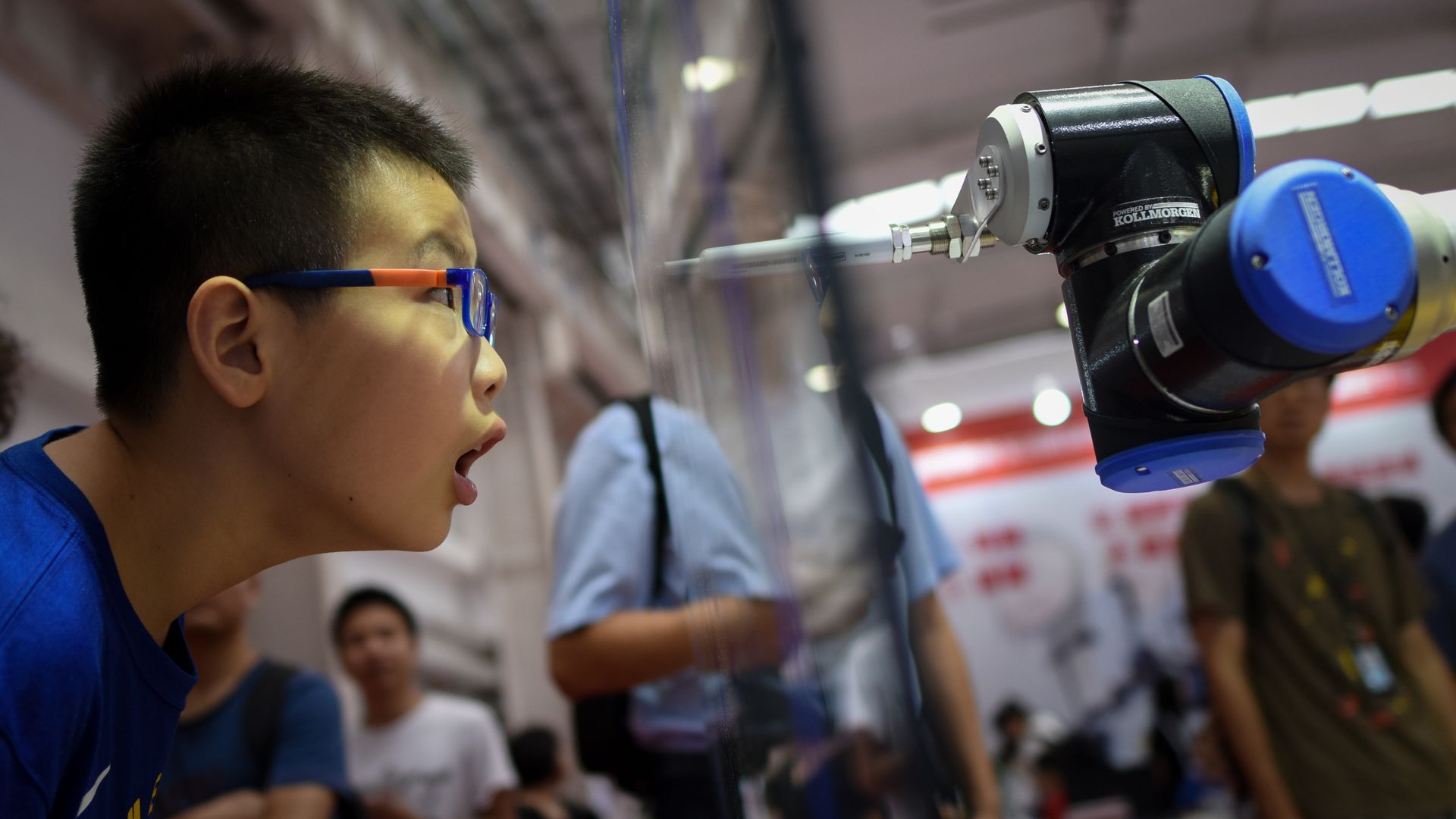 A boy looks closely at a robot arm