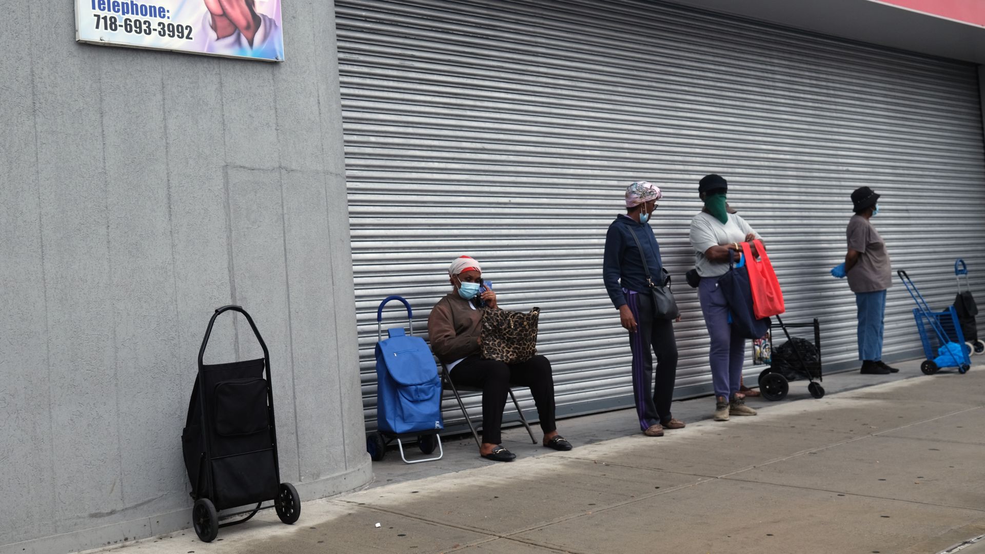 People wait in line at a food distribution site in a Brooklyn neighborhood