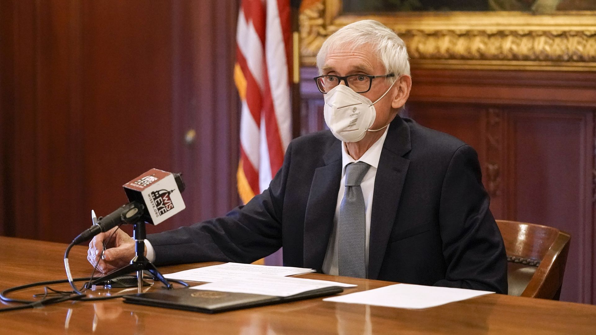 Photo of a masked Tony Evers speaking into a mic