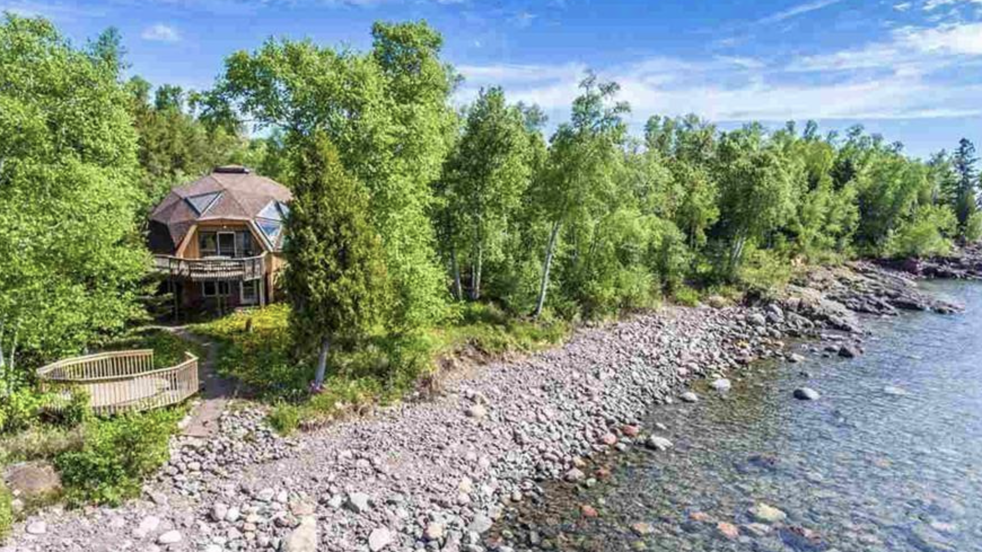 A dome home in the forest with Lake Superior visible in the foreground.