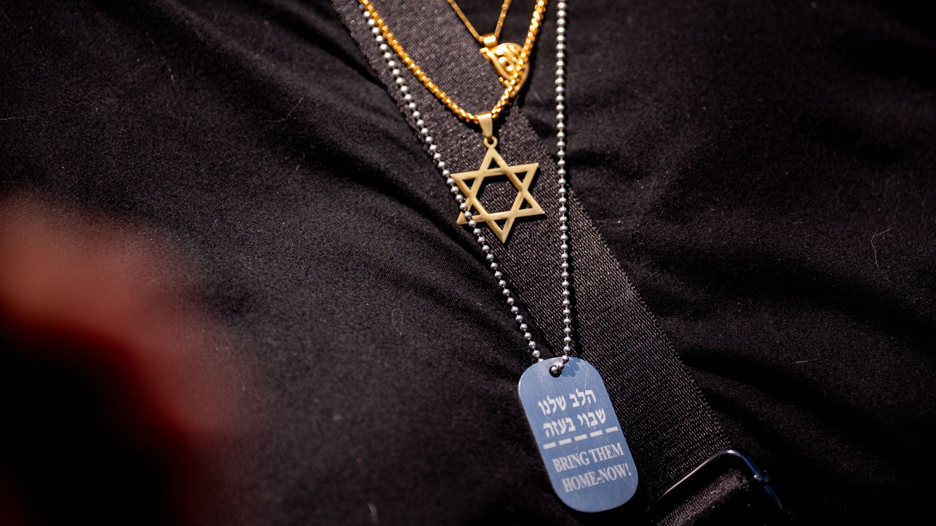 A woman wears the Star of David and another necklace that reads "Bring Them Home Now!" during a rally against campus antisemitism at George Washington University on May 2, 2024 in Washington.