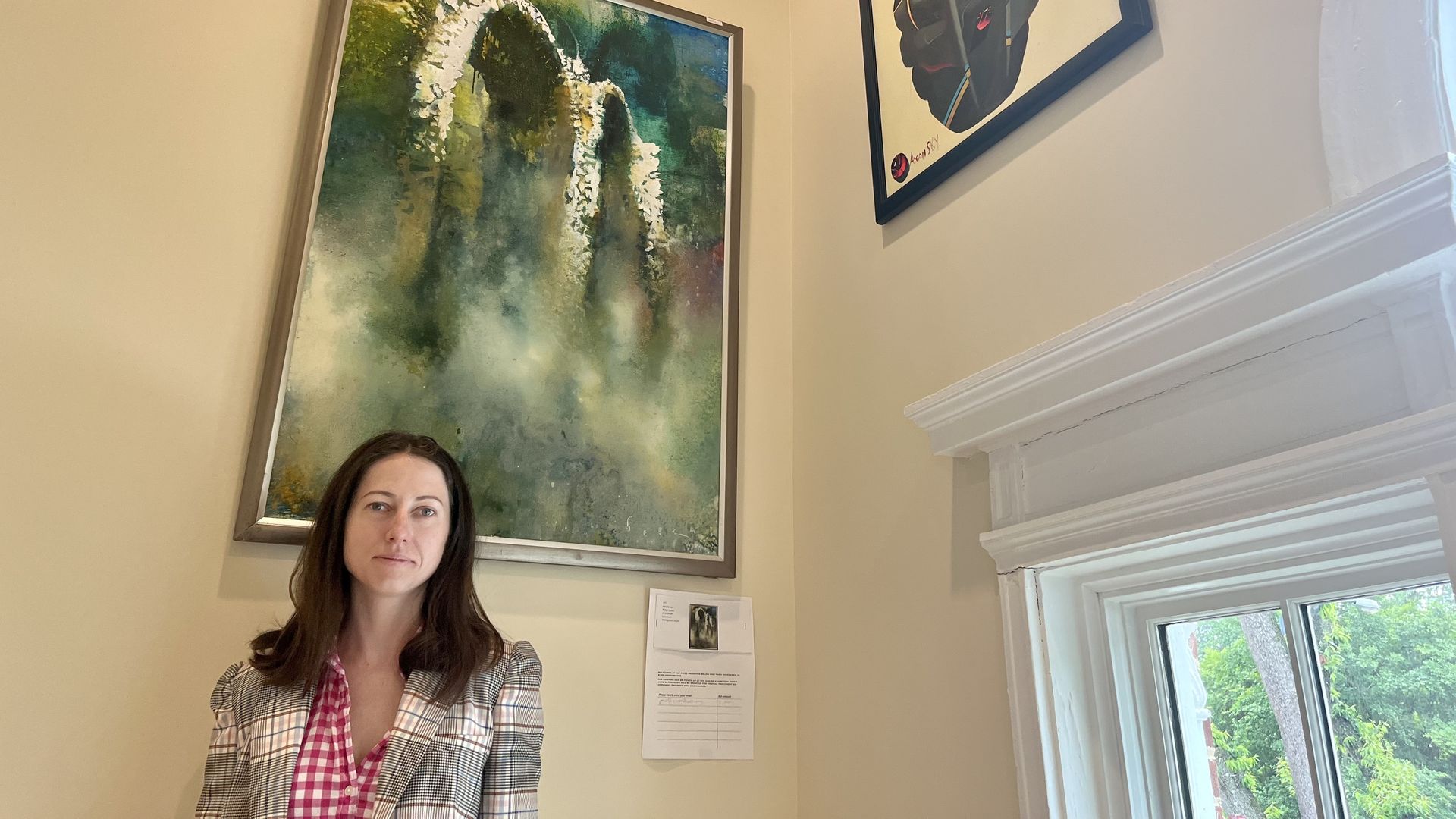 Ukraine House director stands in front of two paintings