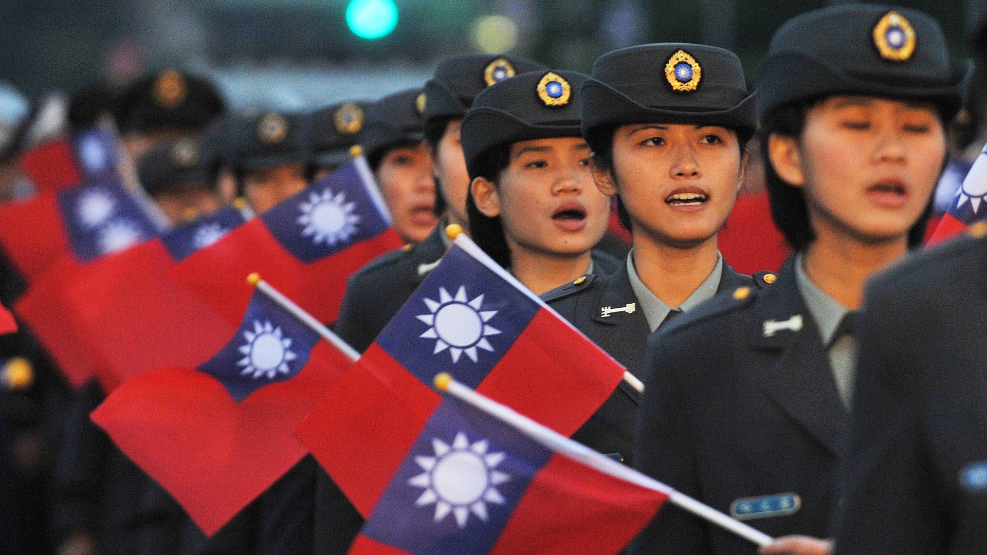 Young women in military uniforms carry Taiwanese flags