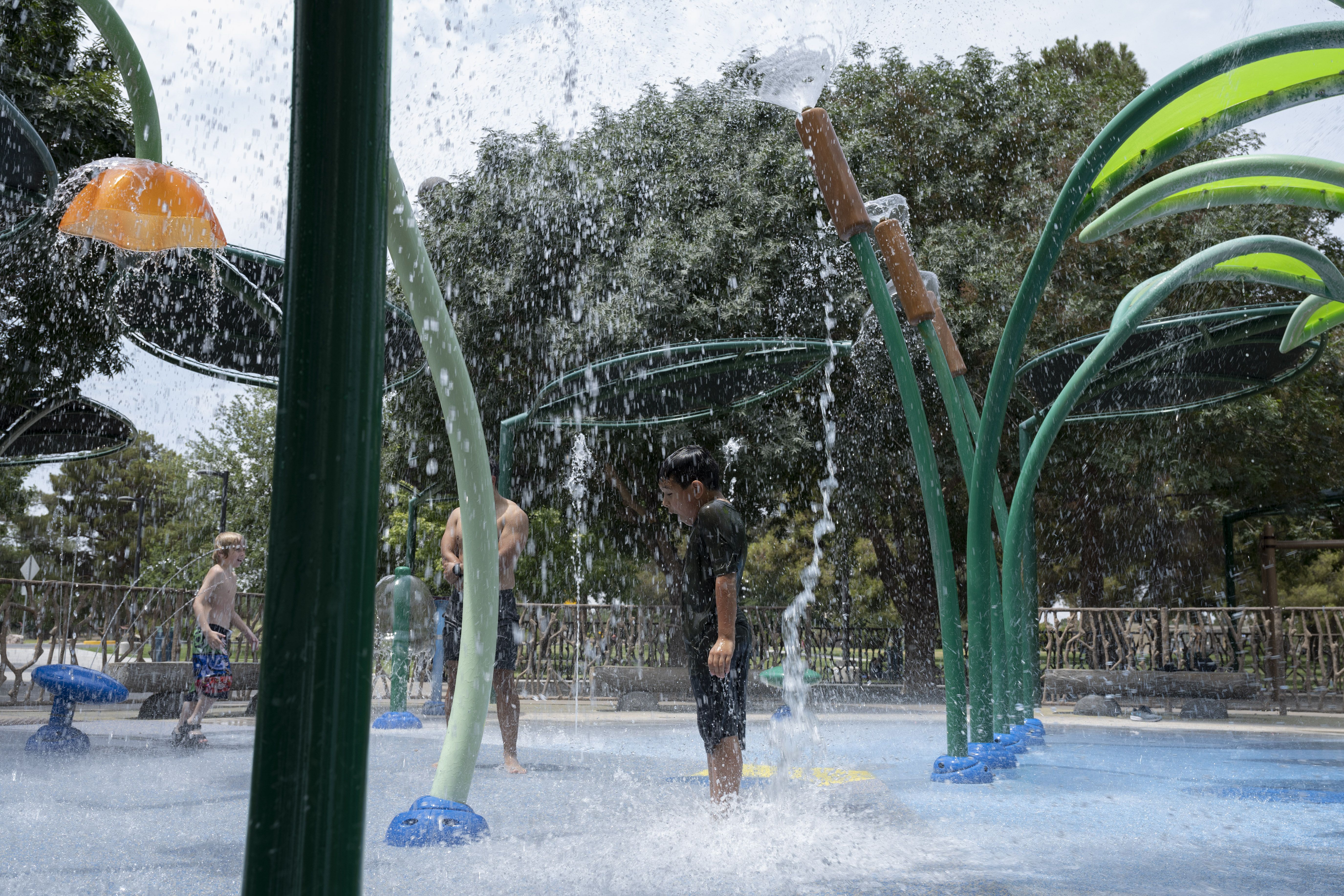 Children cool off in water sprinklers at a park in Las Vegas on June 16, 2021