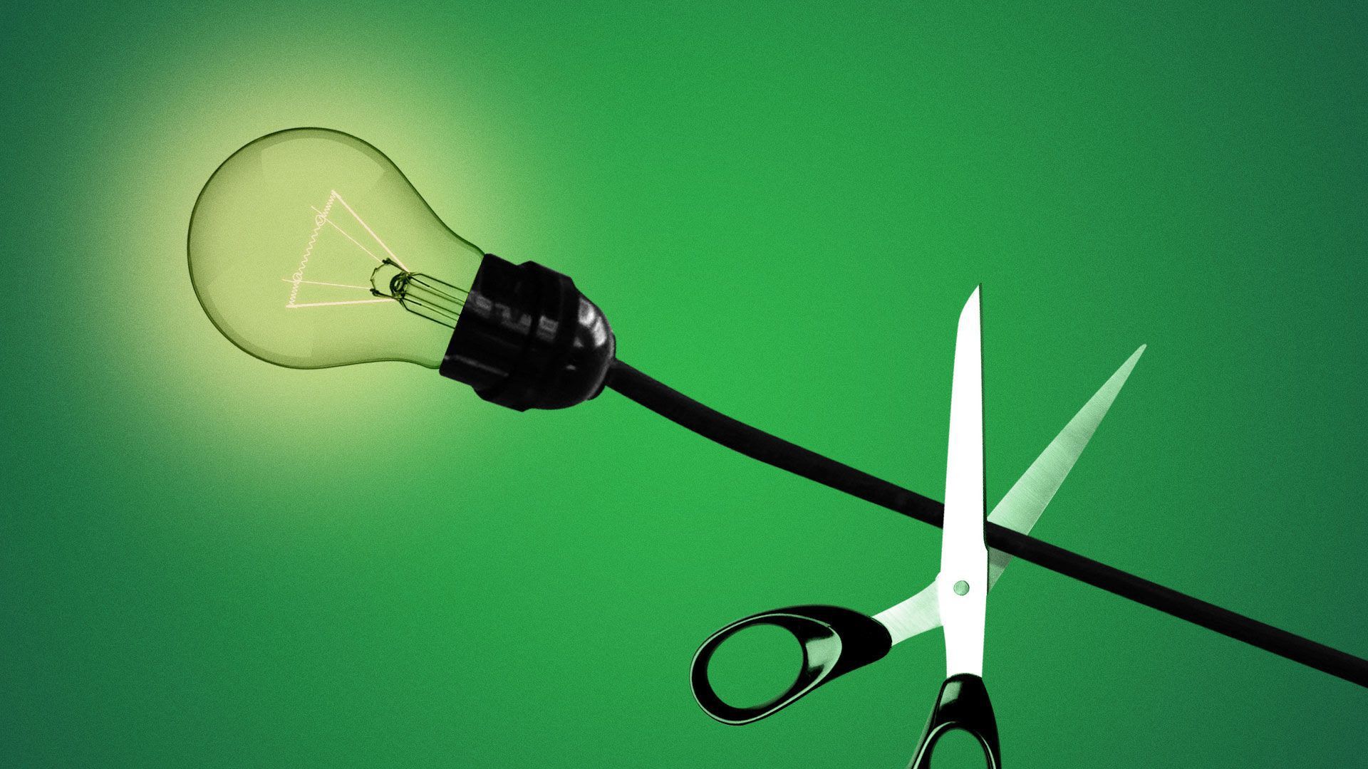 A photo of scissors cutting a light bulb.