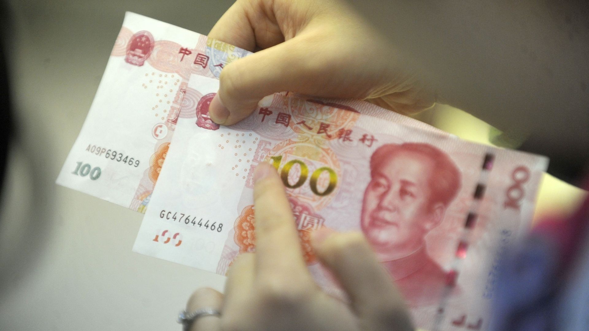A person holds two 100 yuan notes
