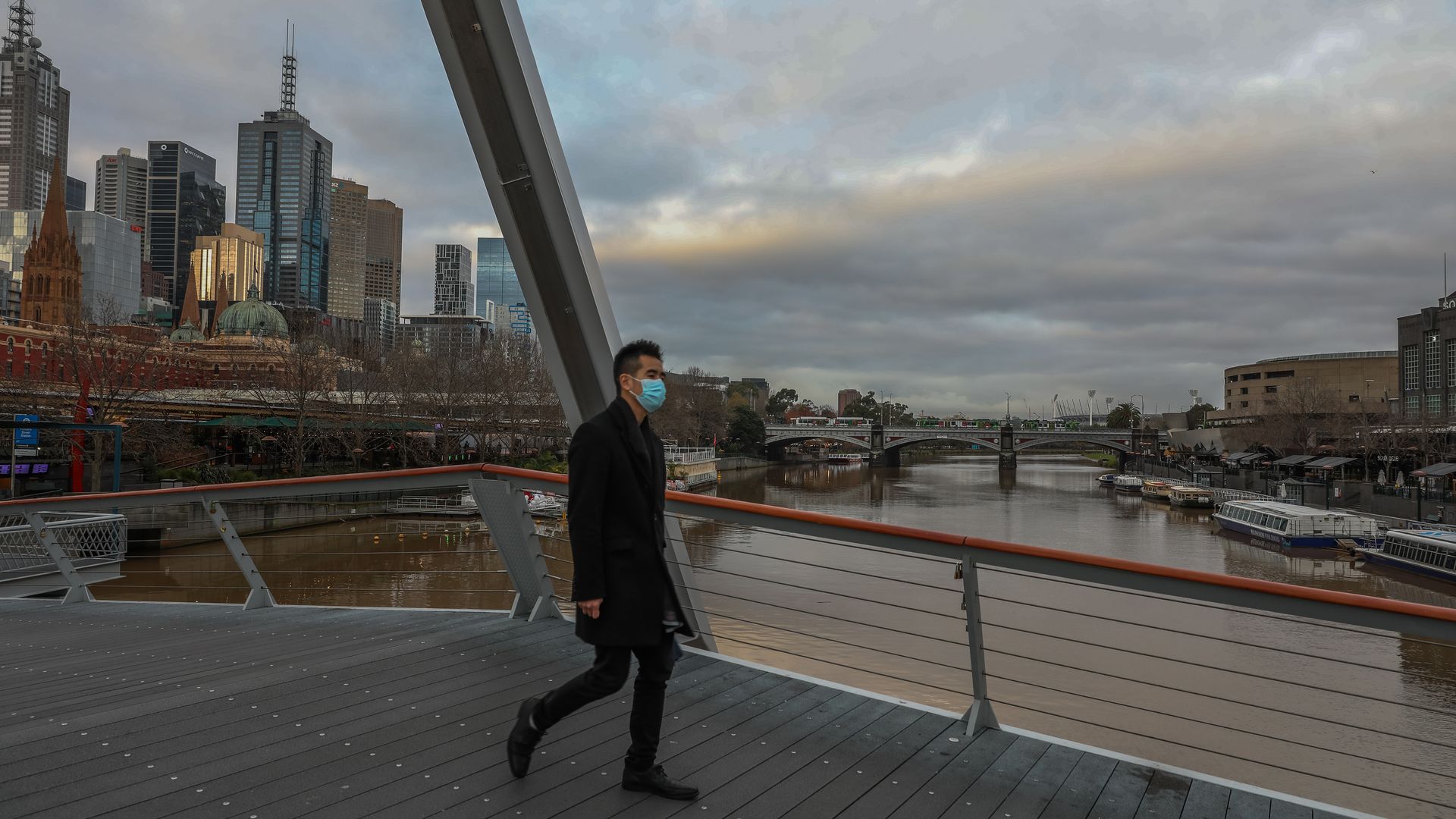 A pedestrian wearing a mask walks over a bridge along the Yarra River on June 11, 2021 in Melbourne, Australia.