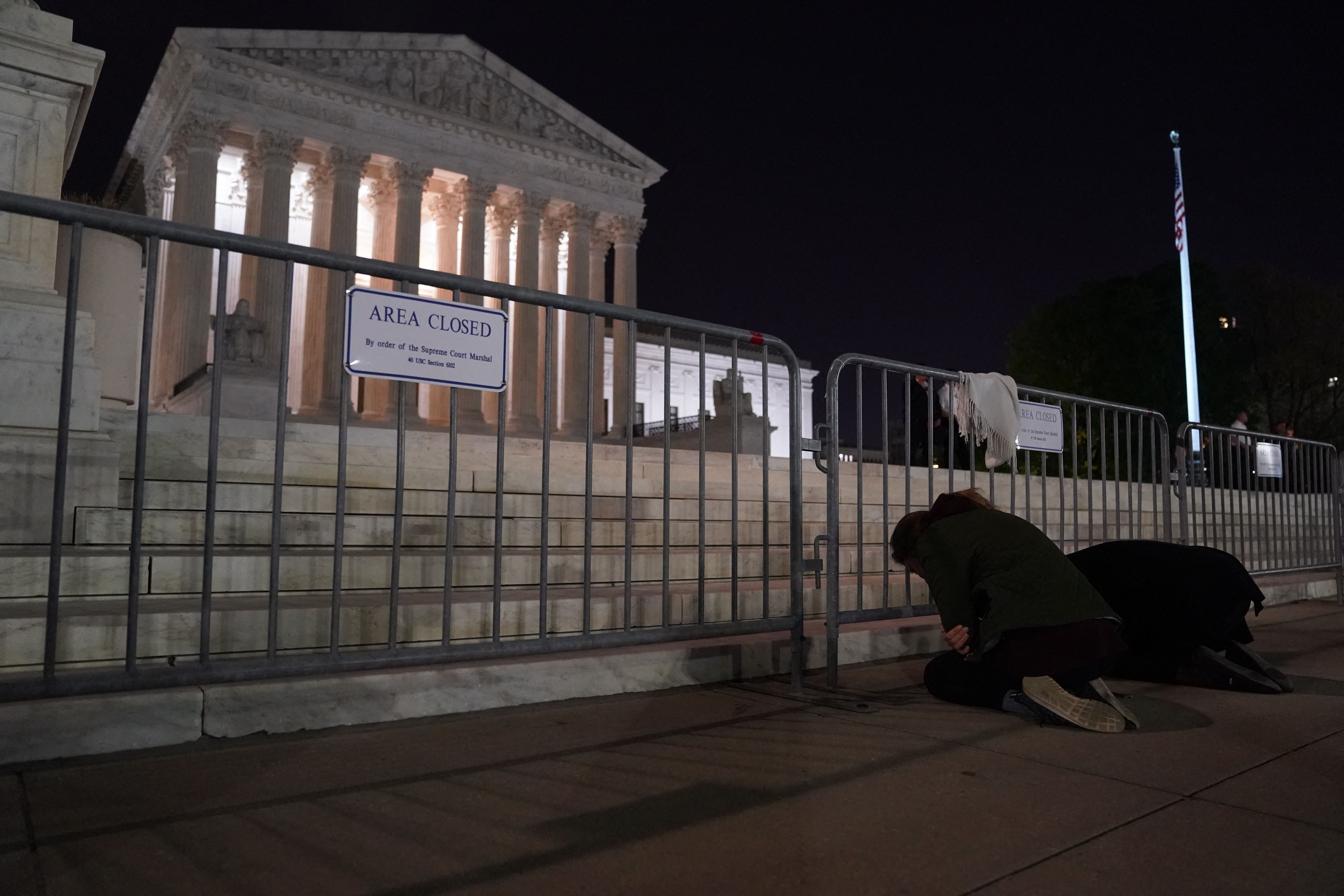 A women cries while kneeling in front of the US Supreme Court in Washington, DC, on May 2