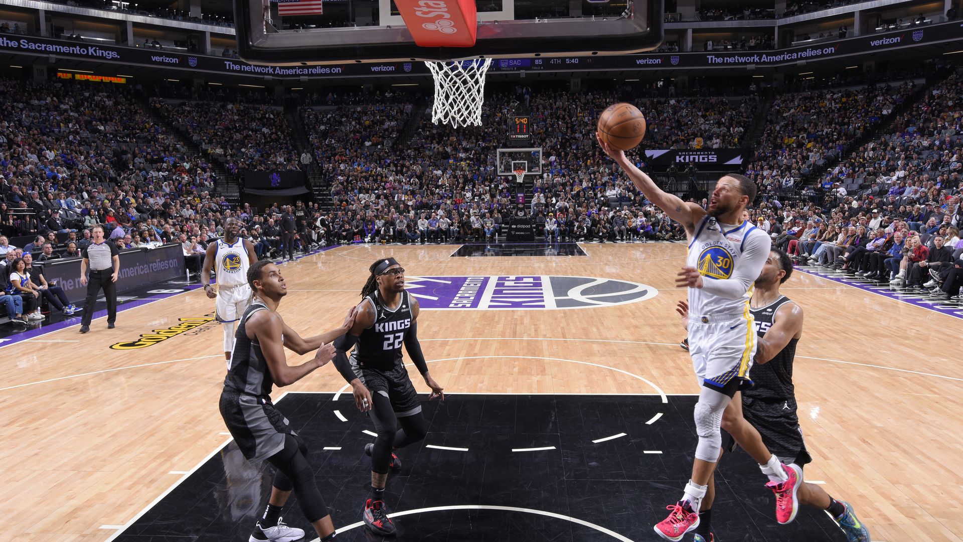 stephen curry, wearing a white jersey, drives toward the hoop for a layup
