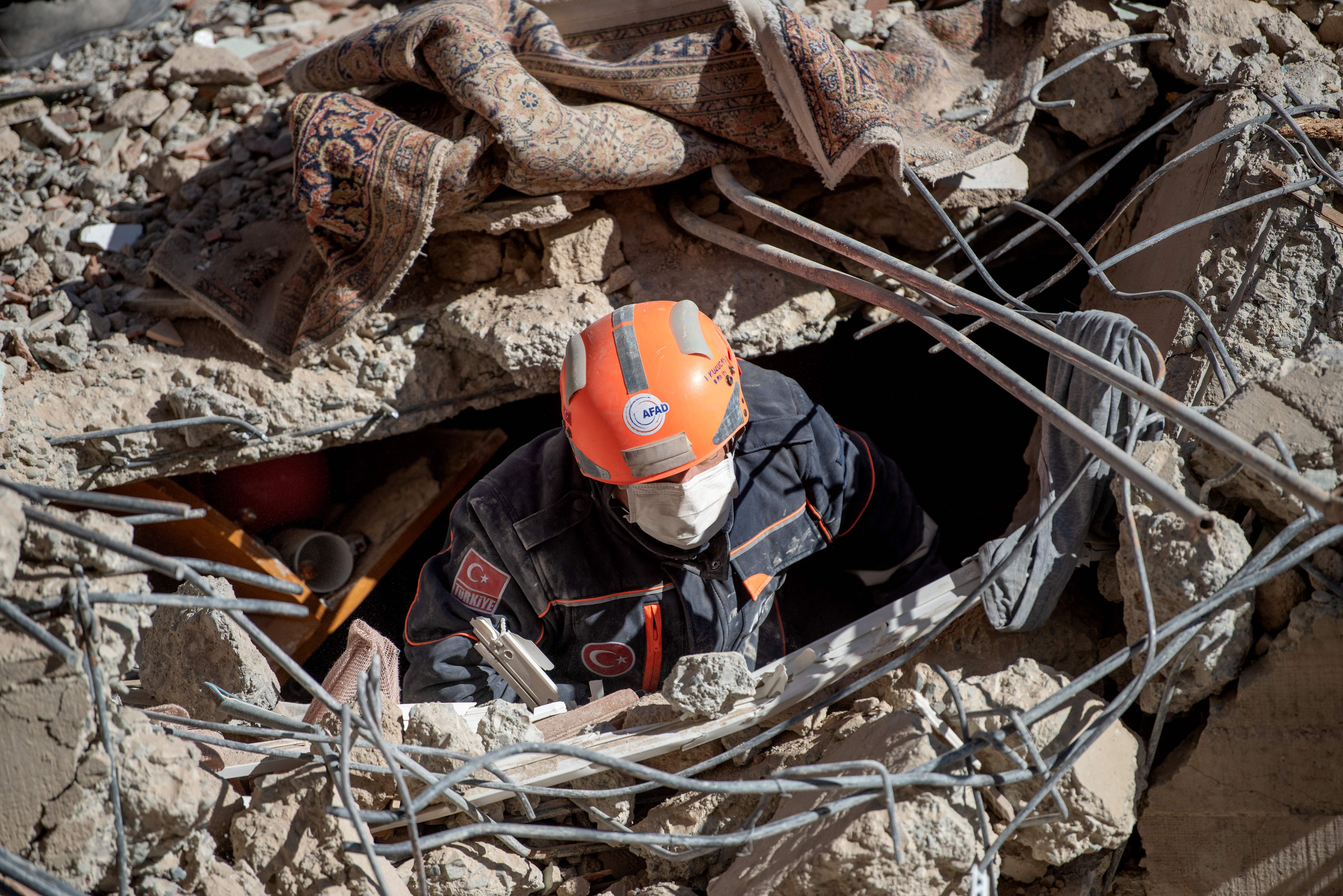 A rescue worker is seen amid the rubble of a building that collapsed due to an earthquake in Elazig