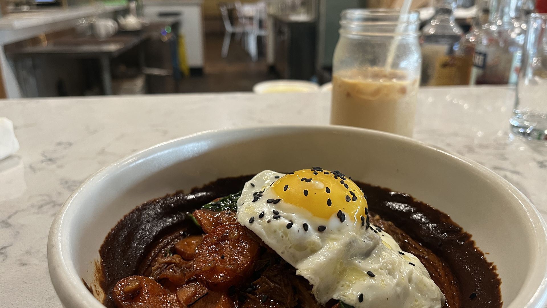 A breakfast dish with an iced coffee in the background.