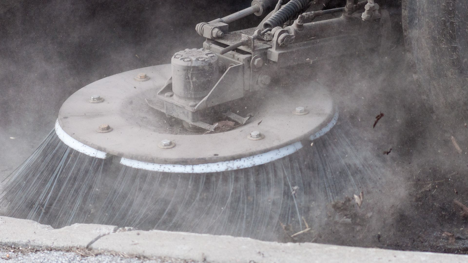 A close up of a mechanical street sweeper.