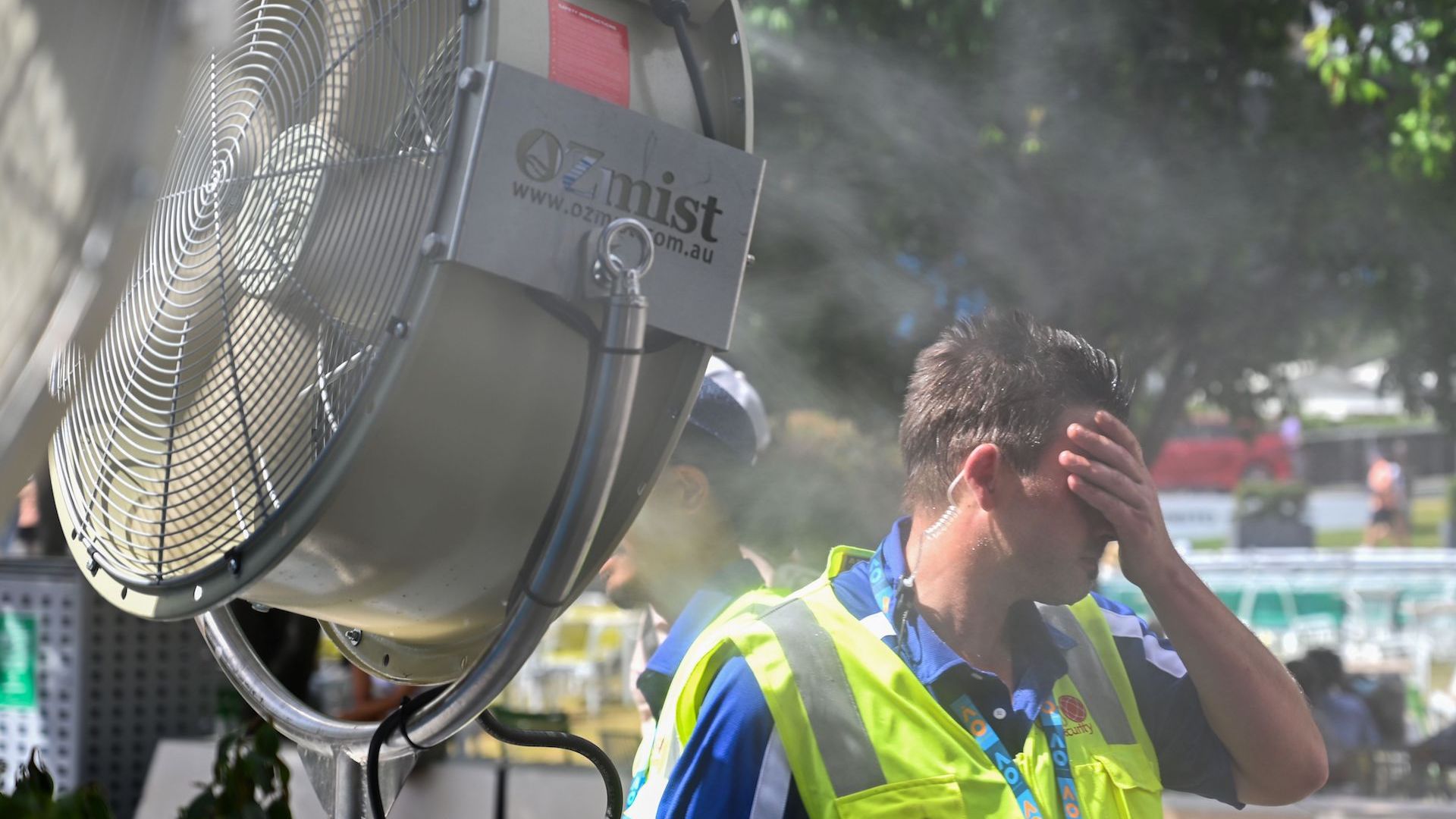 A man cools down in front of a mist fan for relief from the hot weather in Melbourne, Australia.