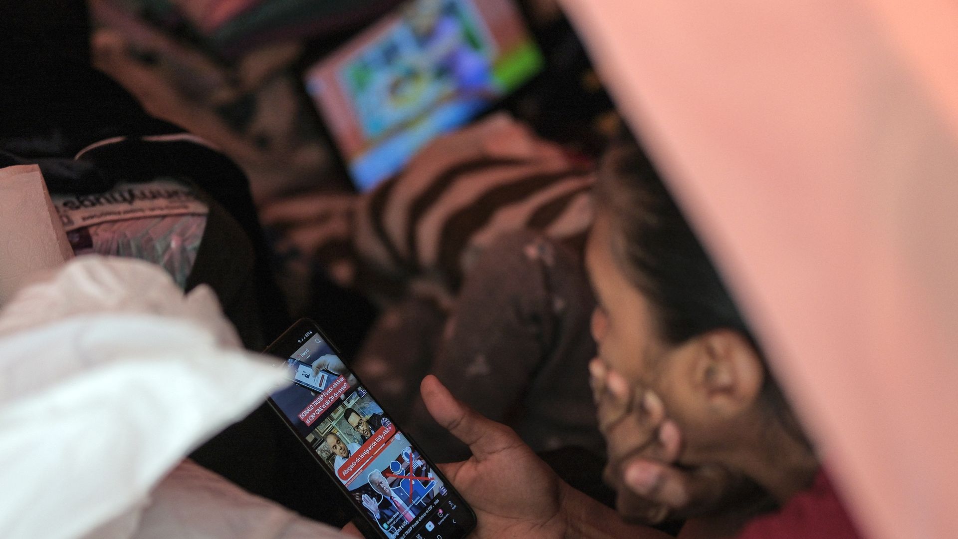 a woman is shown holding her face with one hand while another holds a cellphone showing that Donald Trump won the election.
