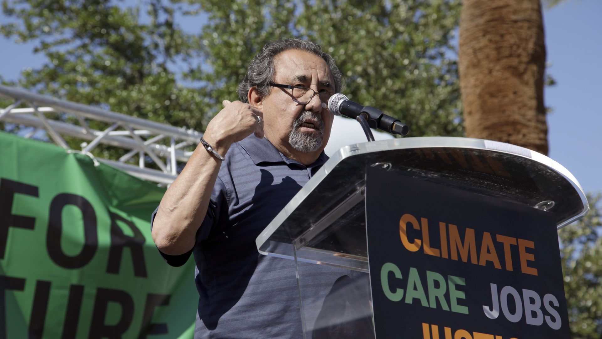 Raul Grijalva speaks at a lectern with a sign on the front emblazoned with the words "climate", "care", "jobs" and "justice."