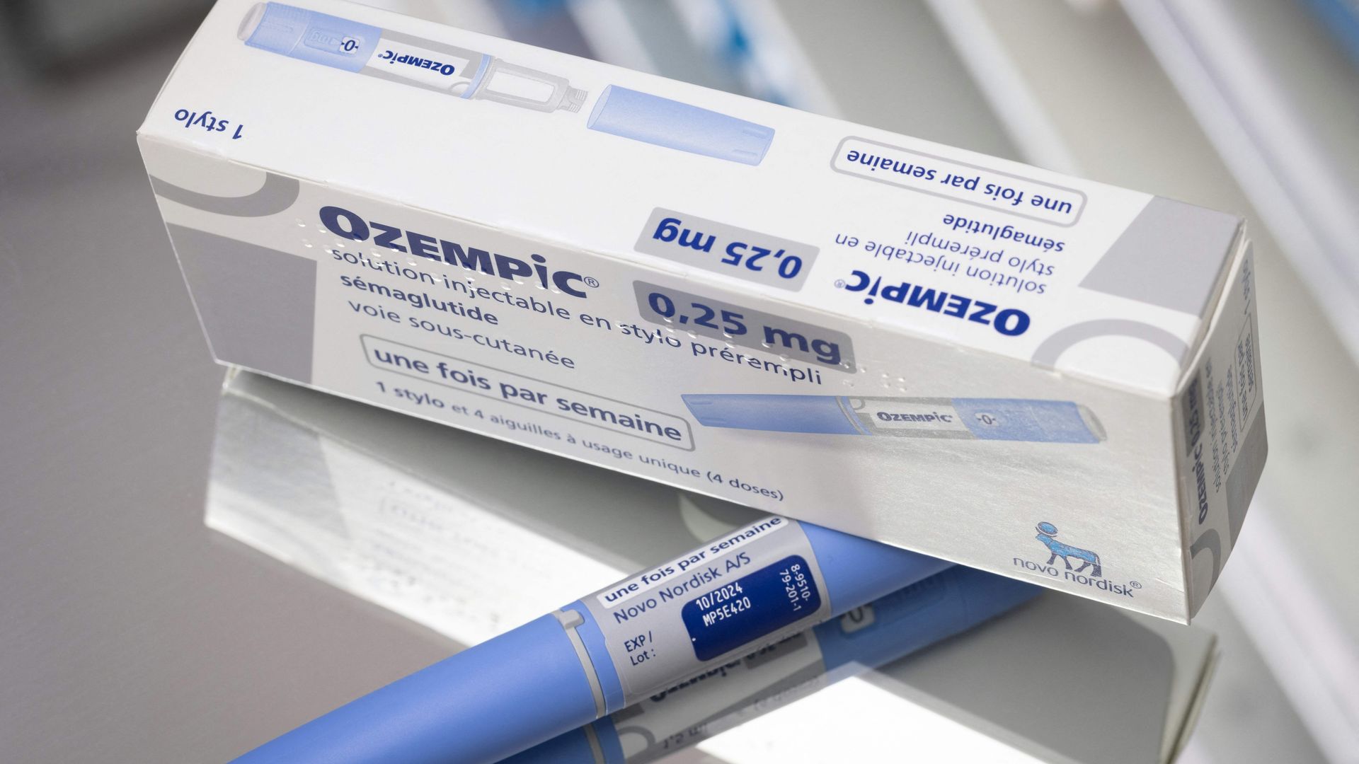 A rectangular white box of medicine sits on top of a blue pen