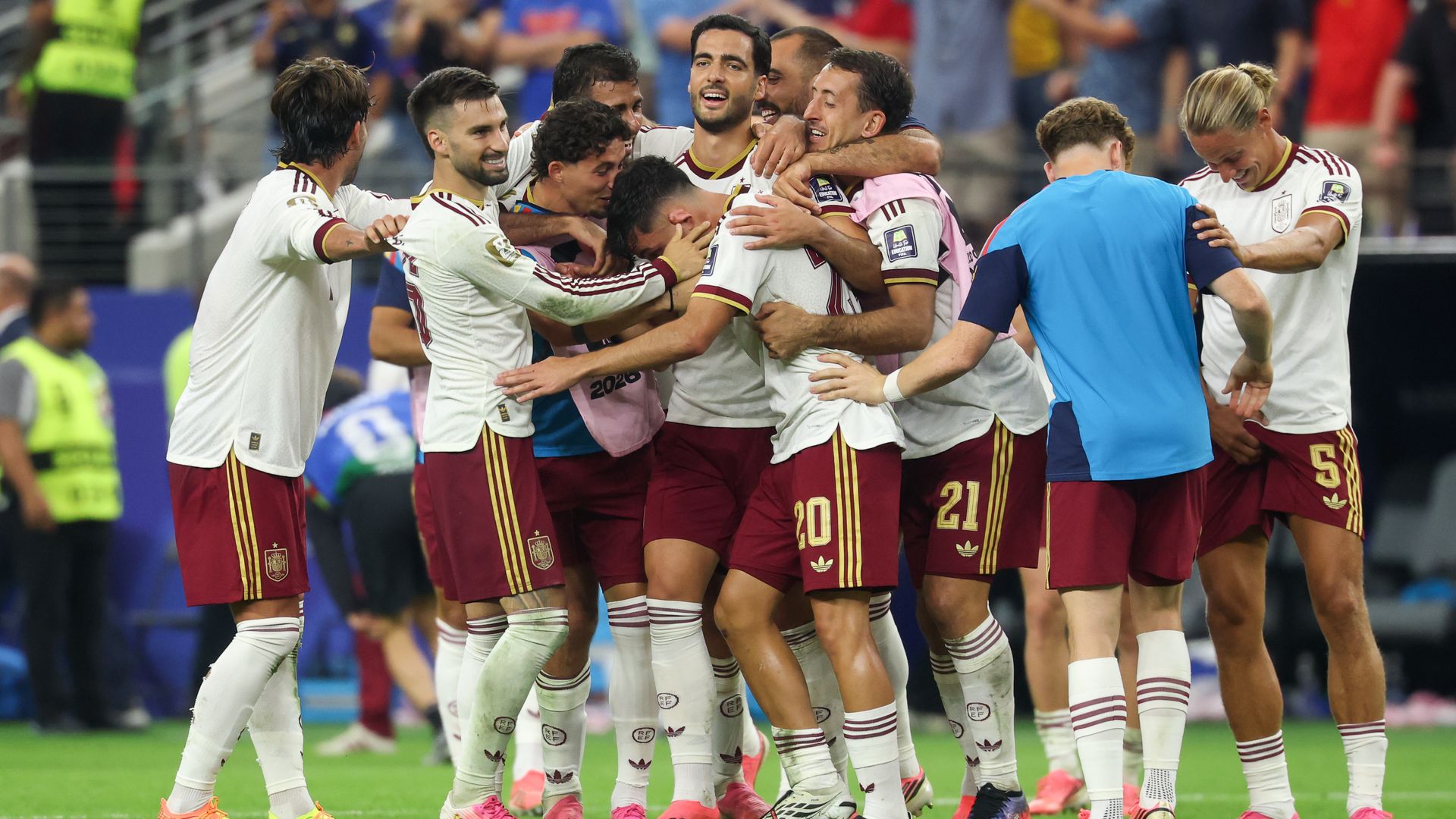 Spain players huddle around each other, smiling