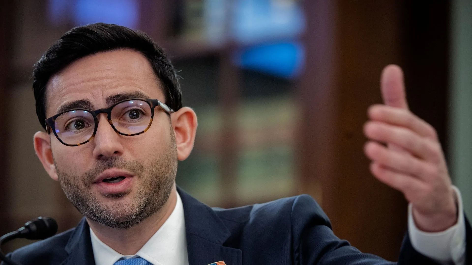 Photo of Samuel Levine wearing glasses gesturing with his hand